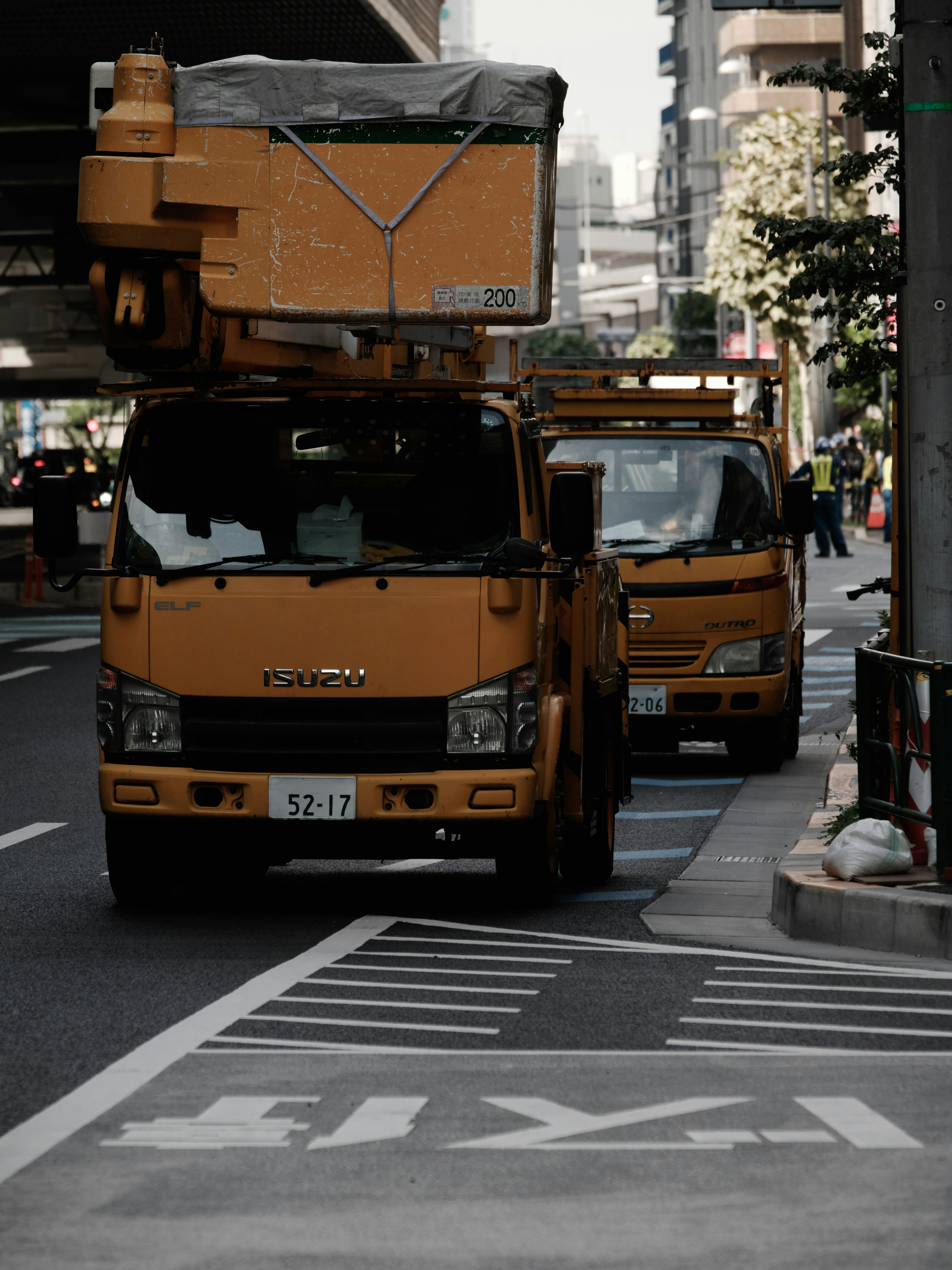 街中に停車している黄色い作業車とその後ろにある別の車両