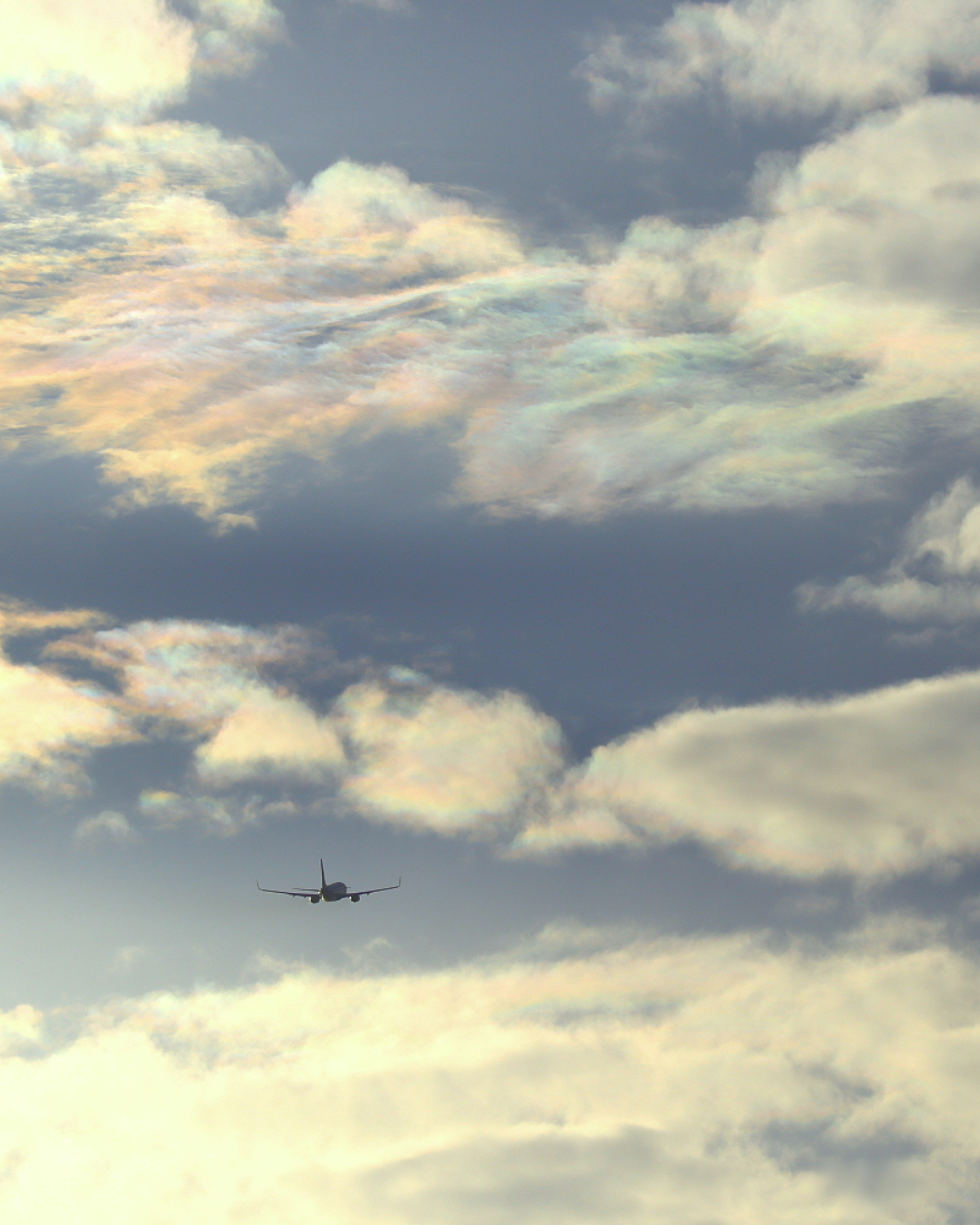 Avión volando en un cielo colorido con nubes iridiscentes