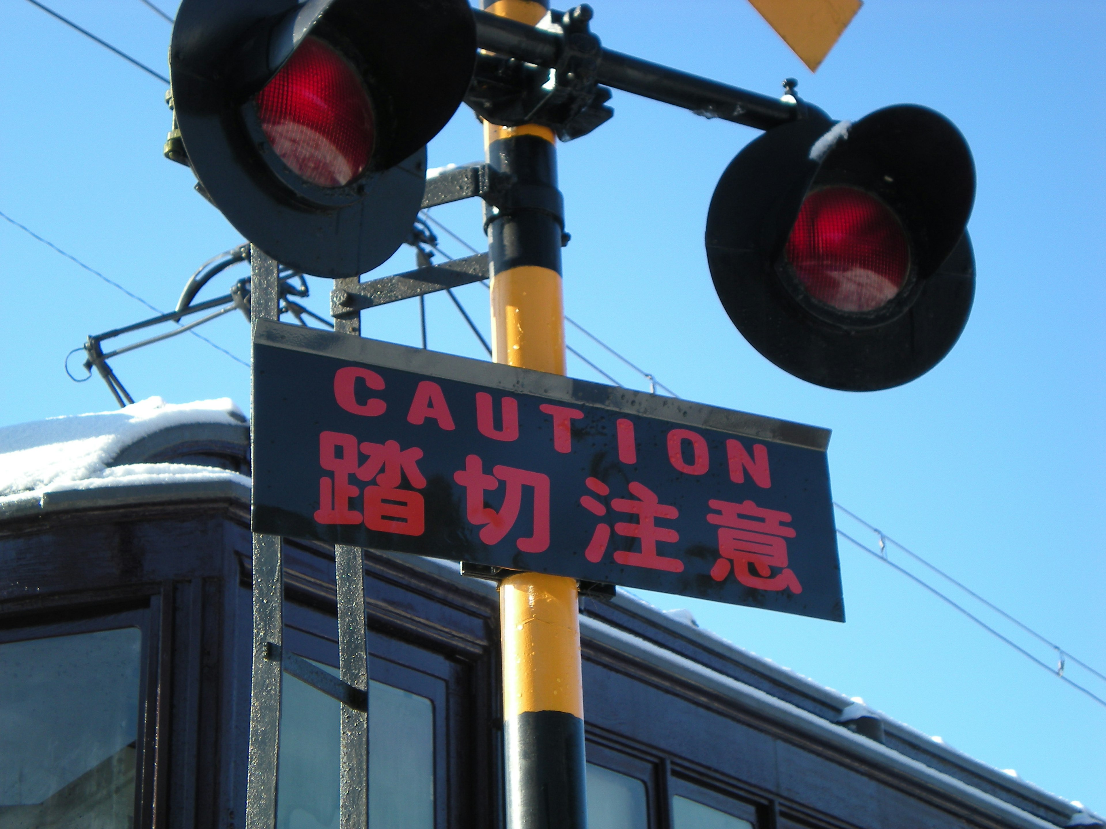 Railroad crossing sign with red lights and caution warning