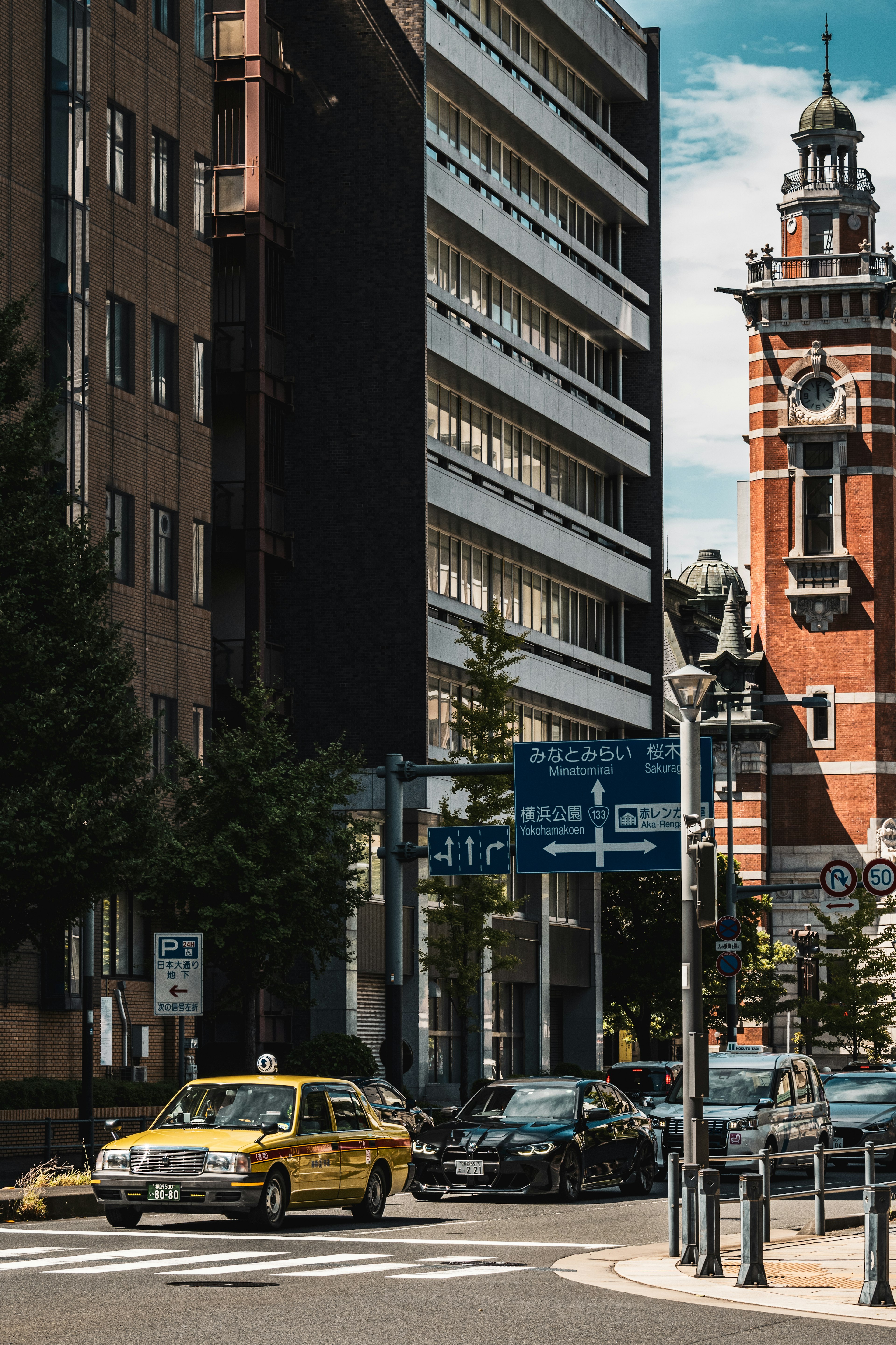 Yellow taxi at an urban intersection with surrounding buildings and street signs