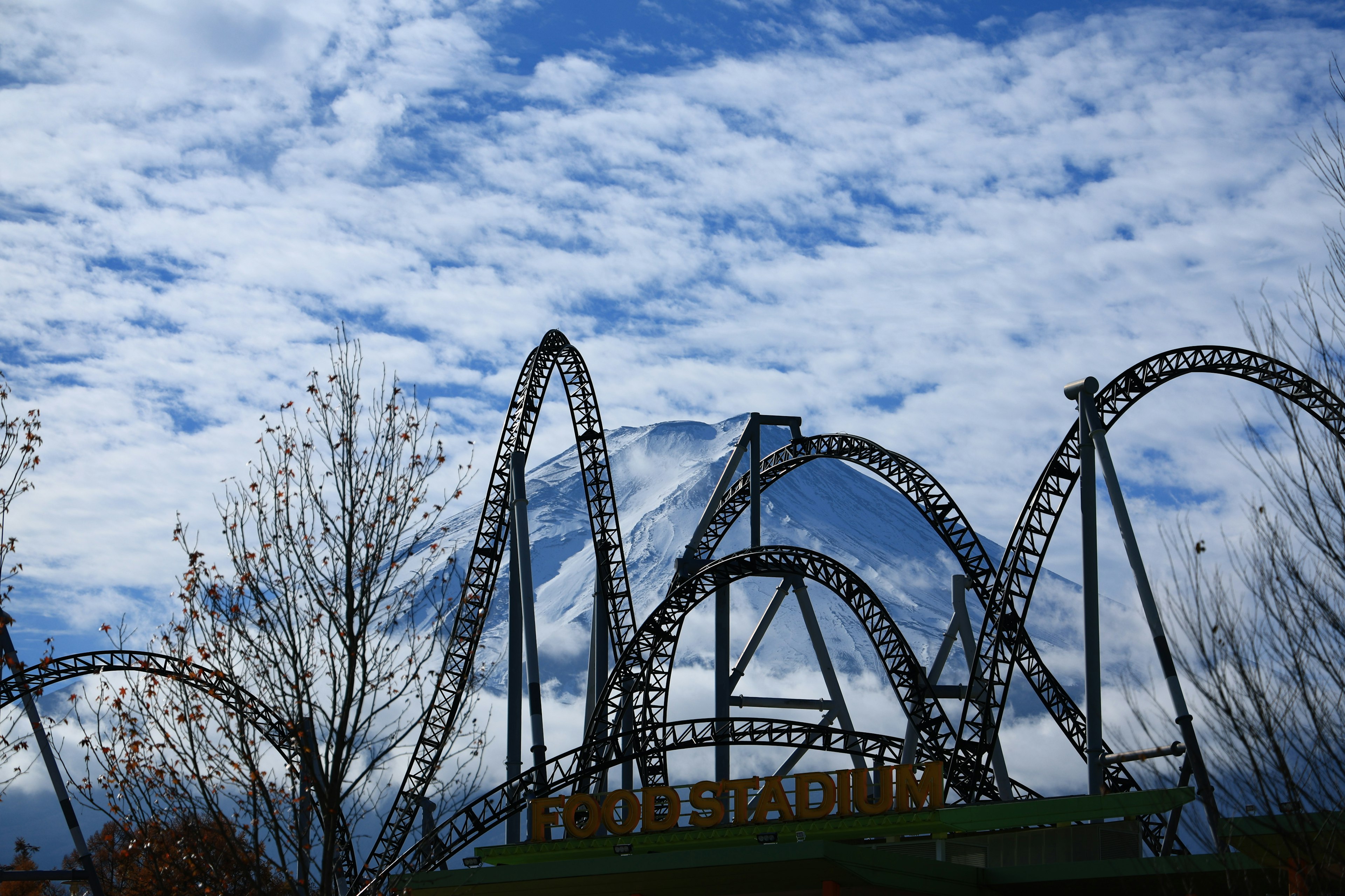 Silhouette of amusement park roller coasters against a blue sky