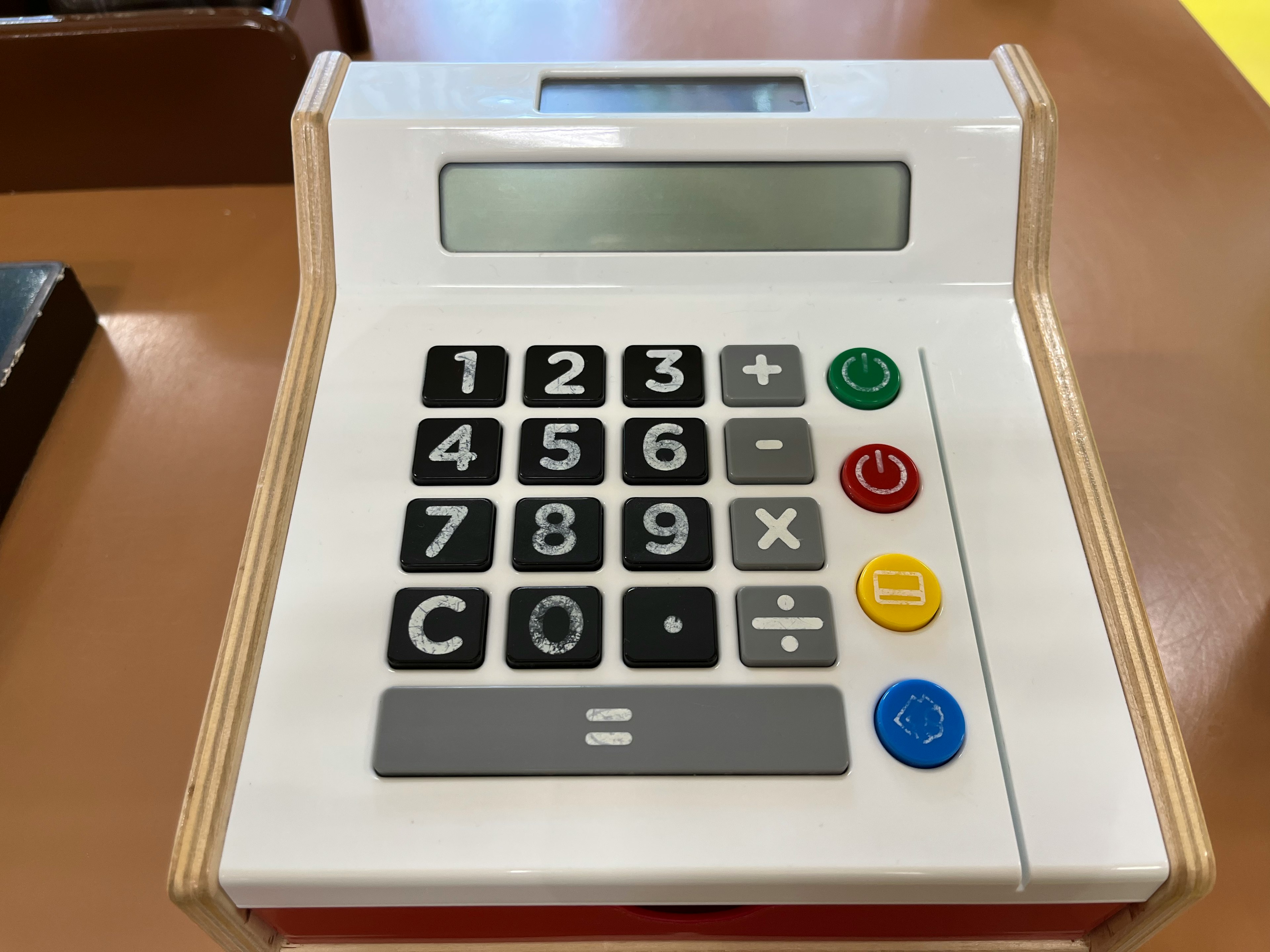 White plastic toy calculator with number buttons and colored function buttons