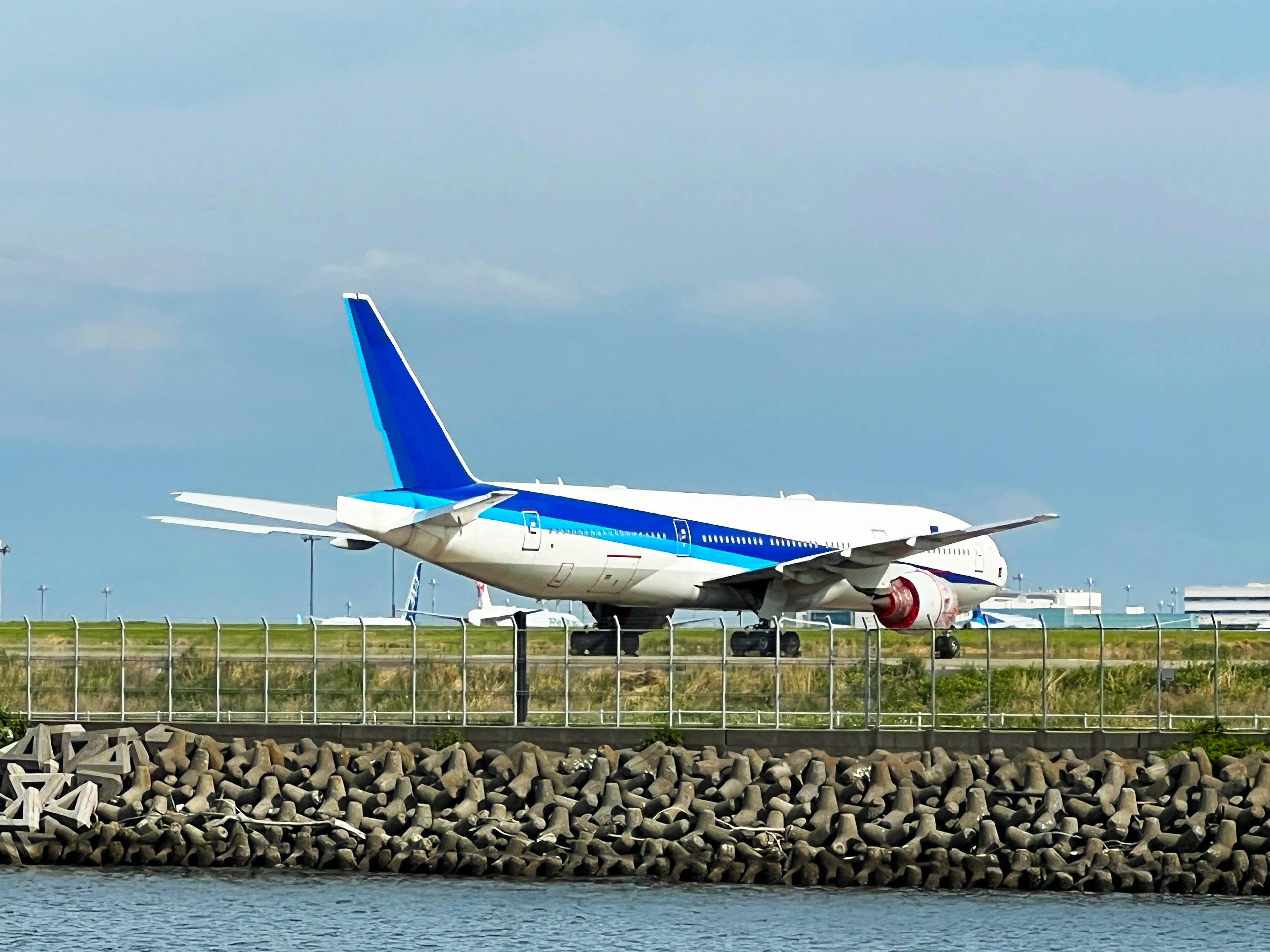 Passagierflugzeug mit blauer Tragfläche in der Nähe der Landebahn geparkt