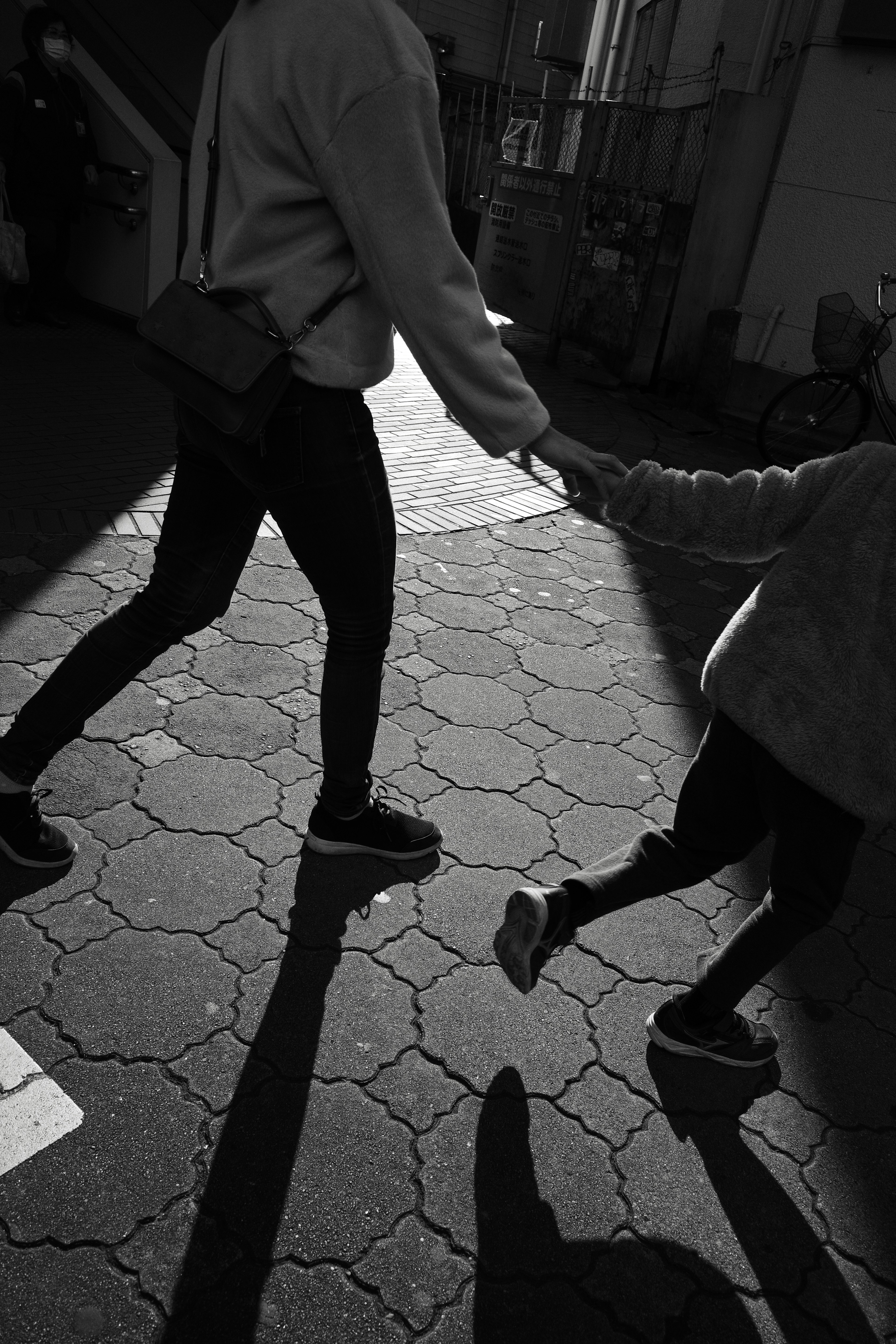 A parent and child holding hands while walking in a black and white photo