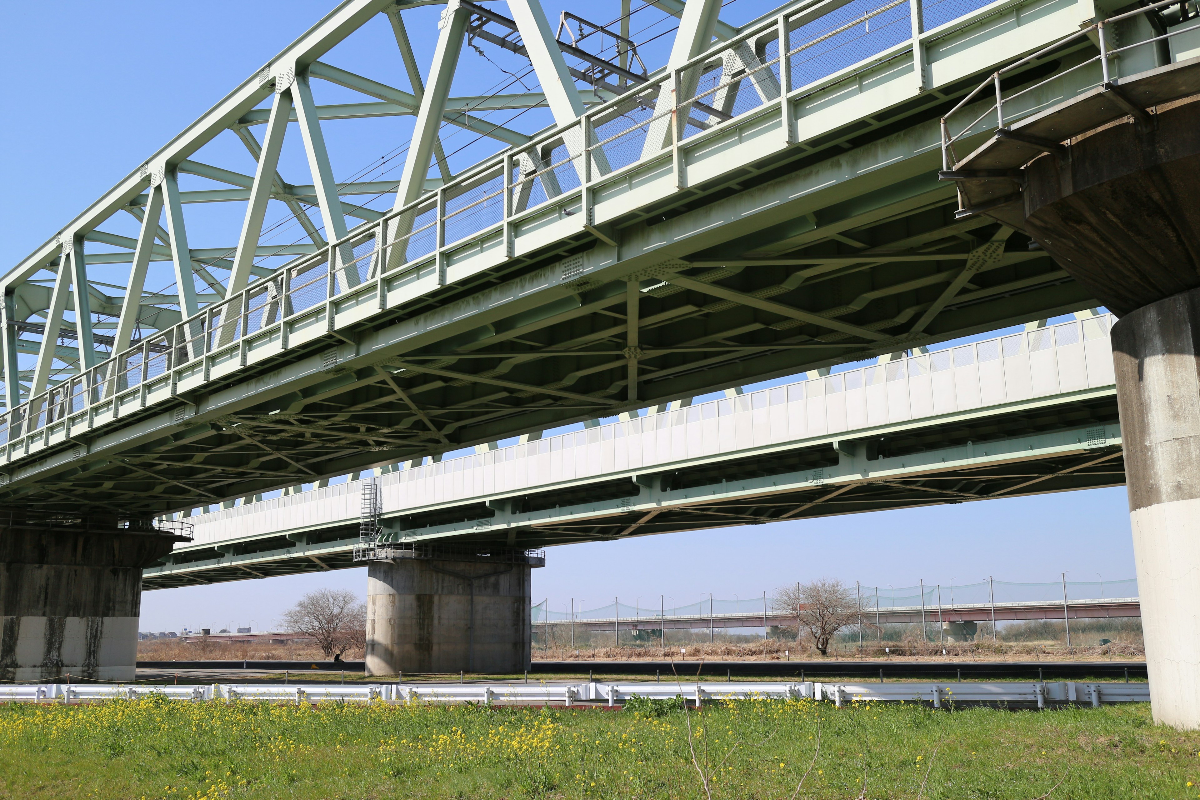 Green metal bridge spanning over a river with structural details