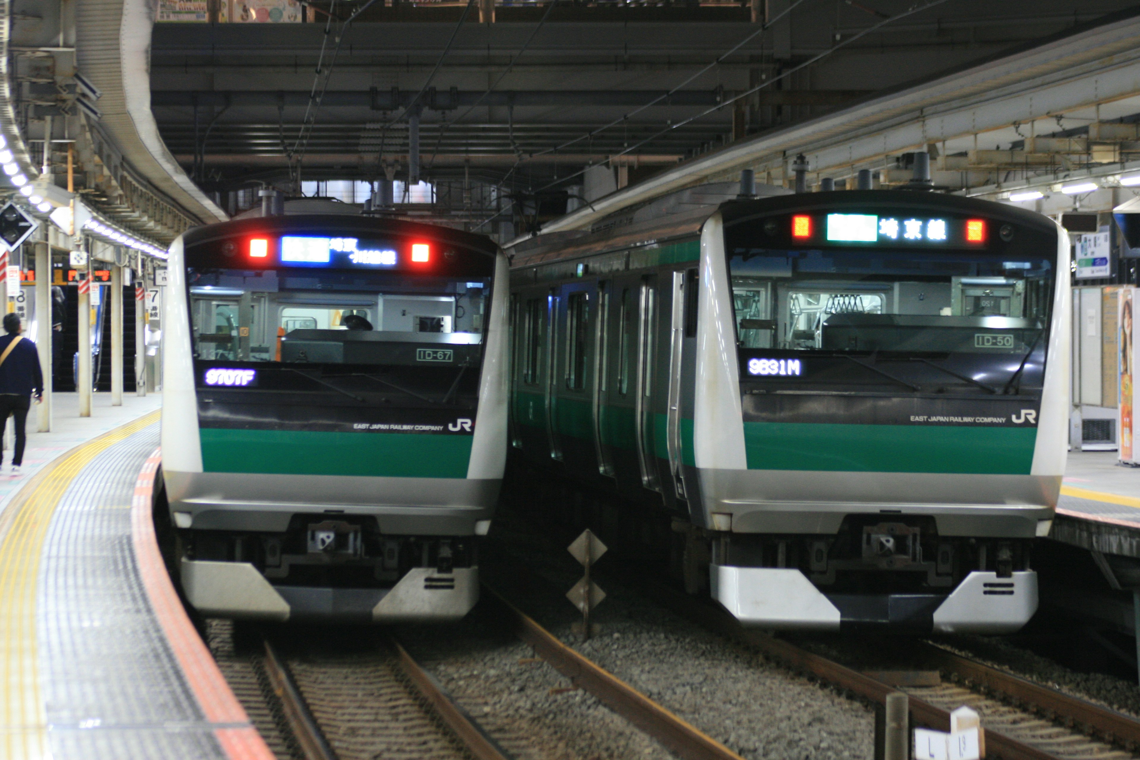 二つの緑色の電車が駅のプラットフォームに停車している