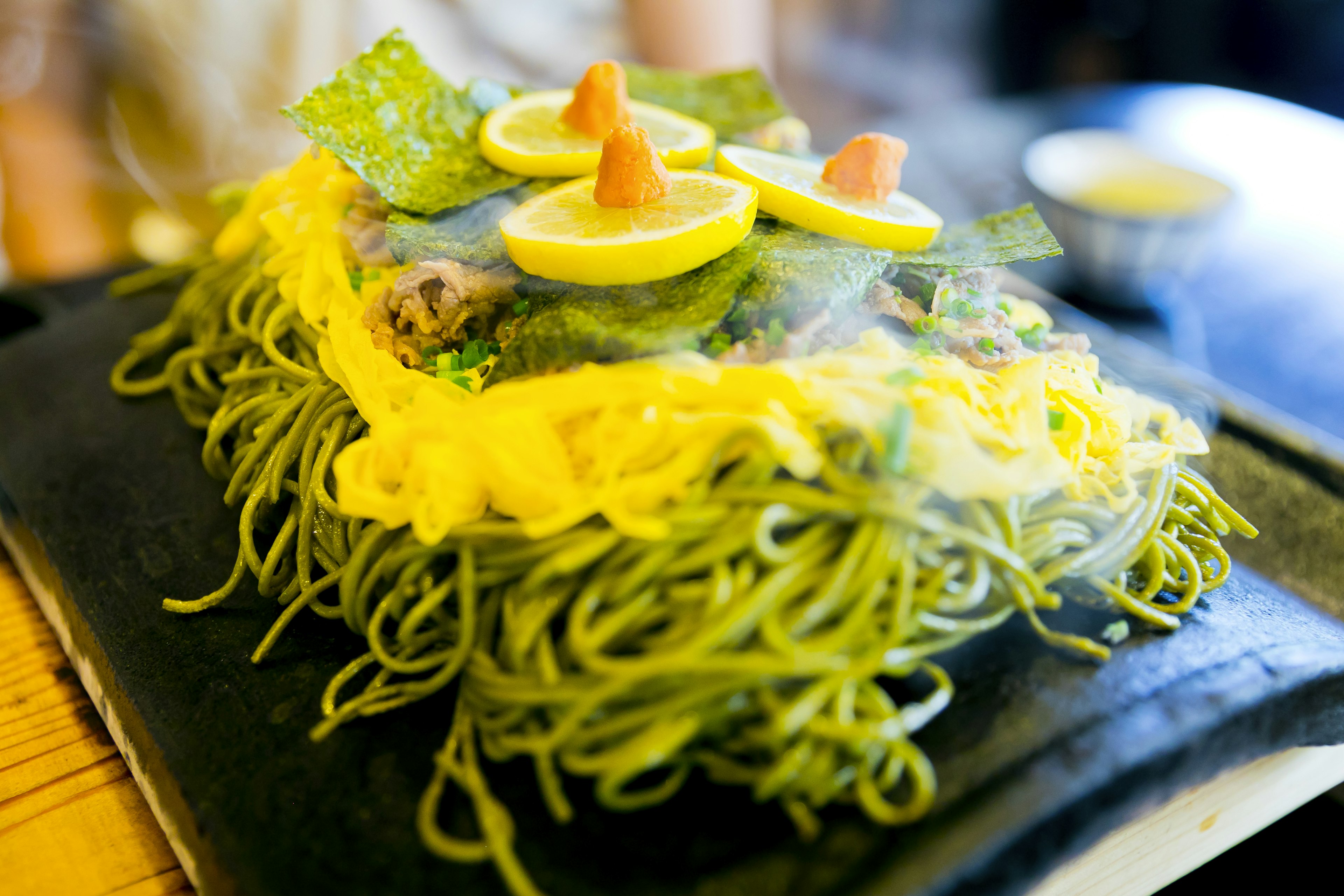 Piatto con noodles verdi guarniti con fette di limone e mandorle