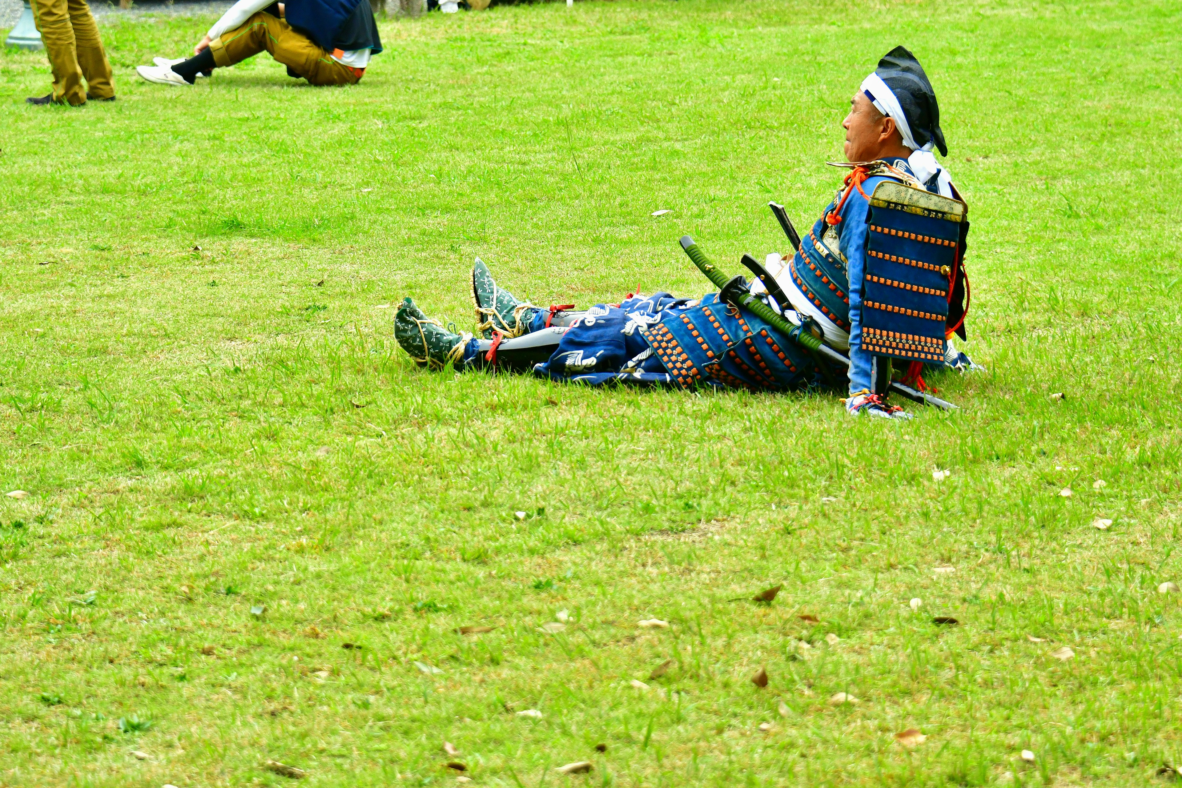 Person in traditioneller Kleidung sitzt auf dem Gras