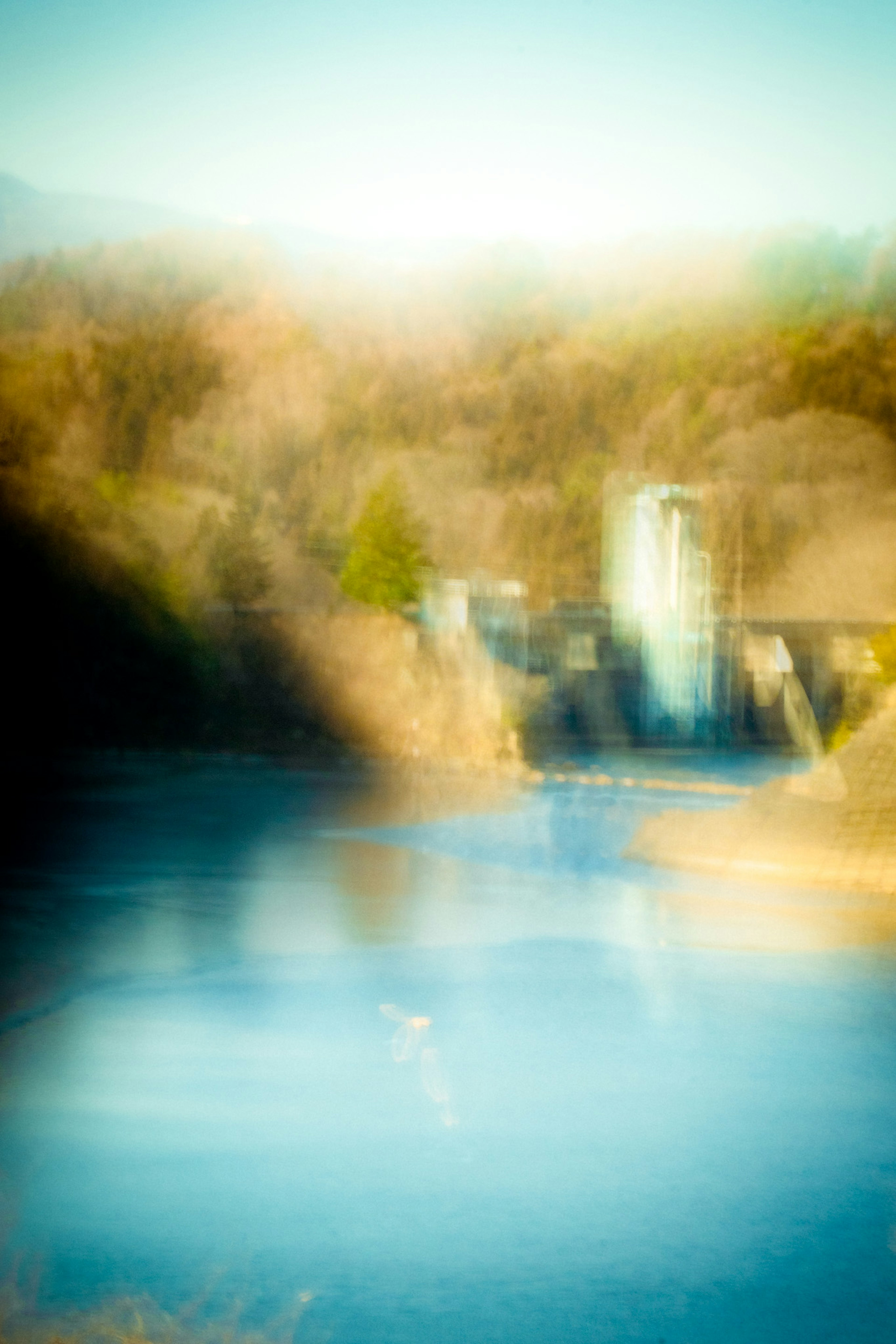 Blurred view of a river with soft reflections and distant buildings