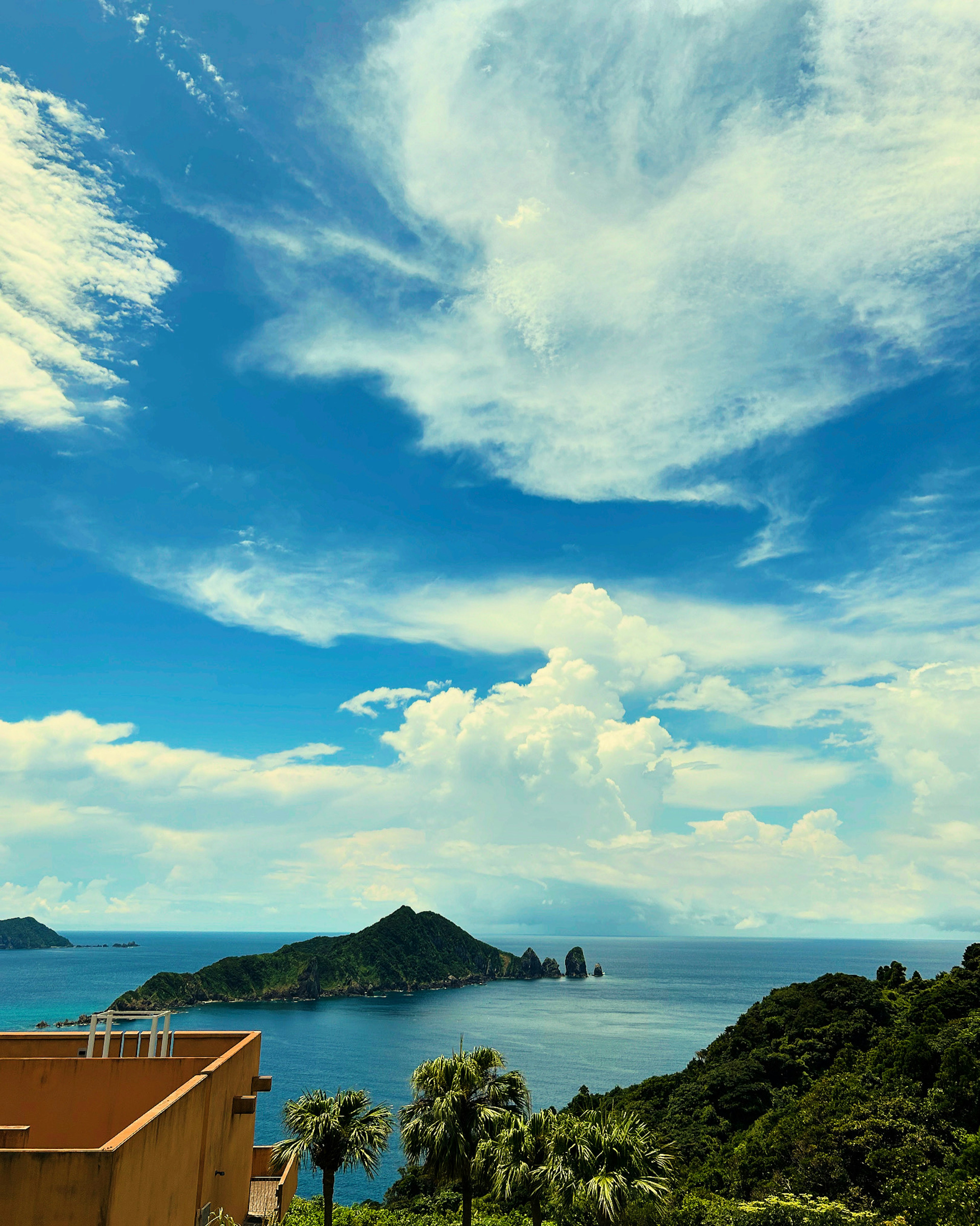 青い空と雲が広がる海の景色 島と山々が見える