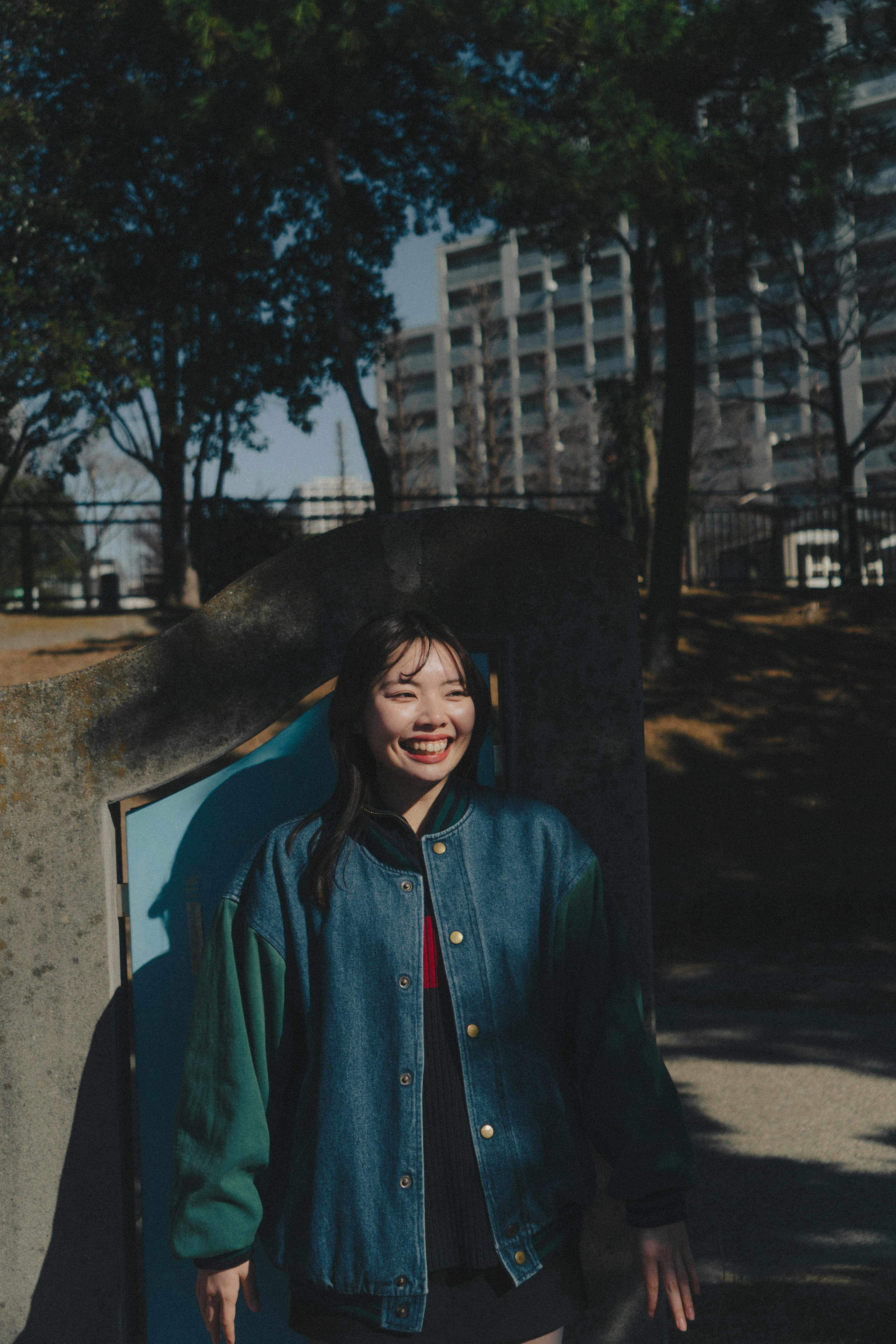 Une femme souriante dans une veste bleue dans un parc