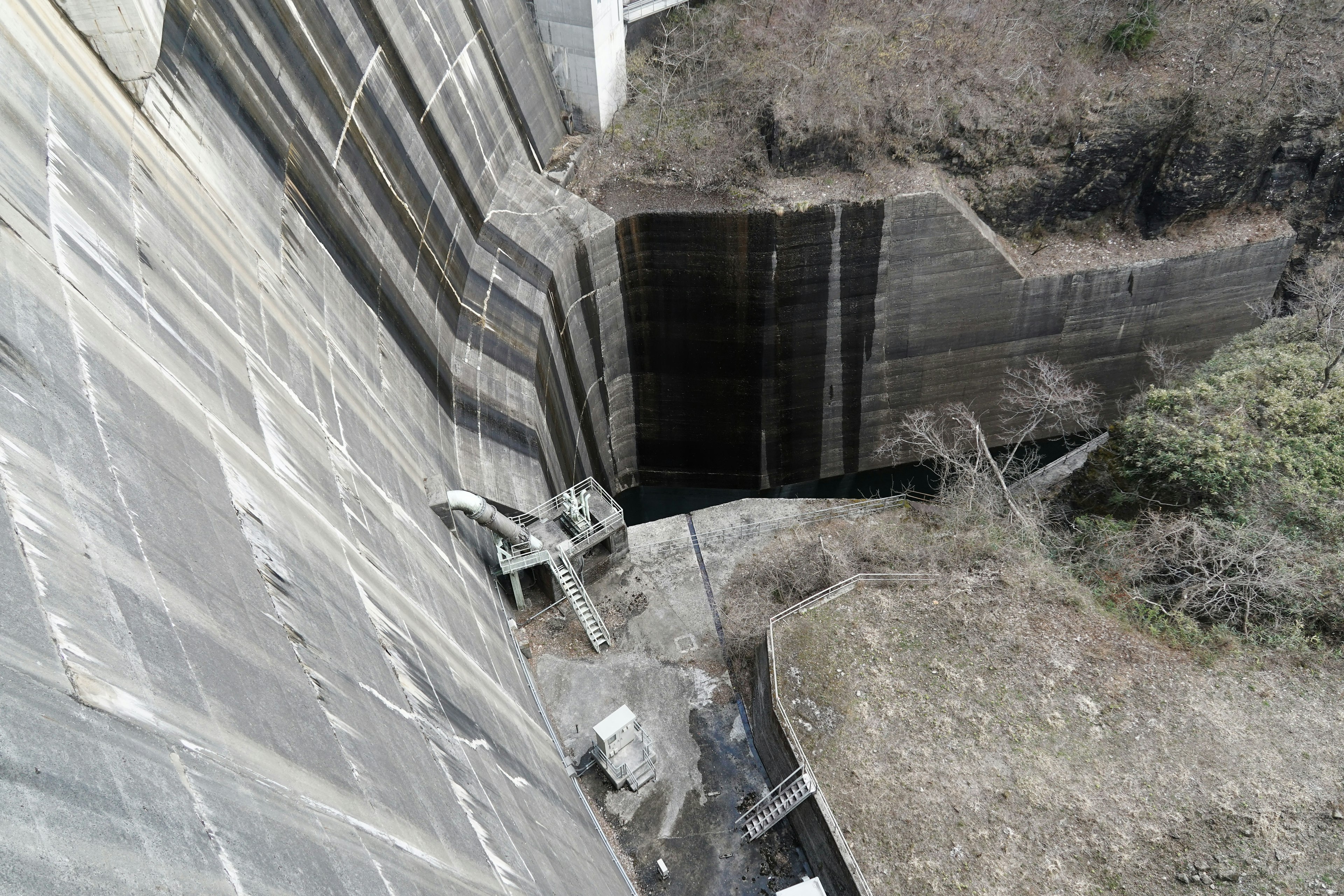 Vue du sommet d'un barrage montrant la structure en béton et le terrain sec environnant