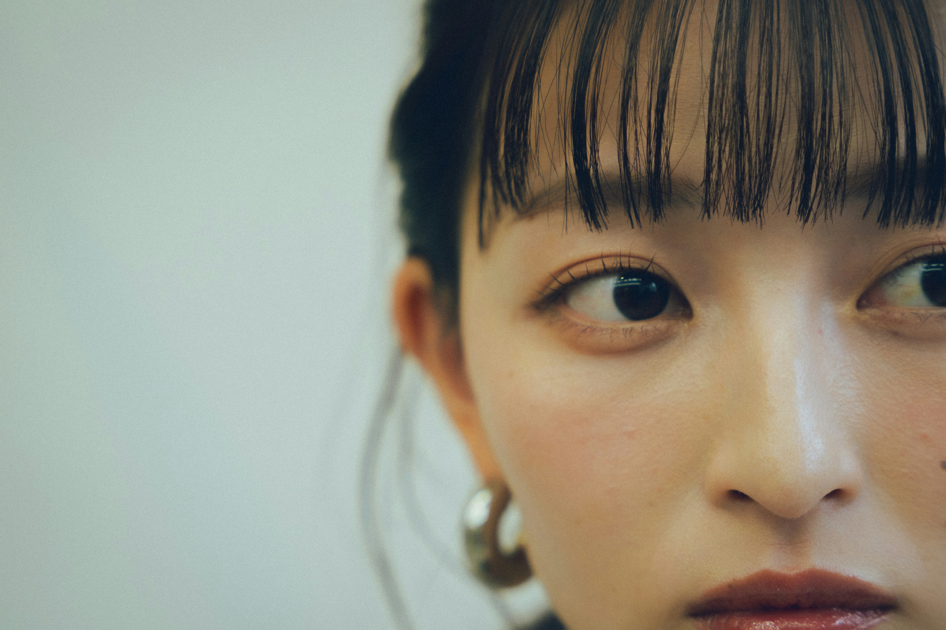 Close-up of a woman's face featuring short bangs and large earrings