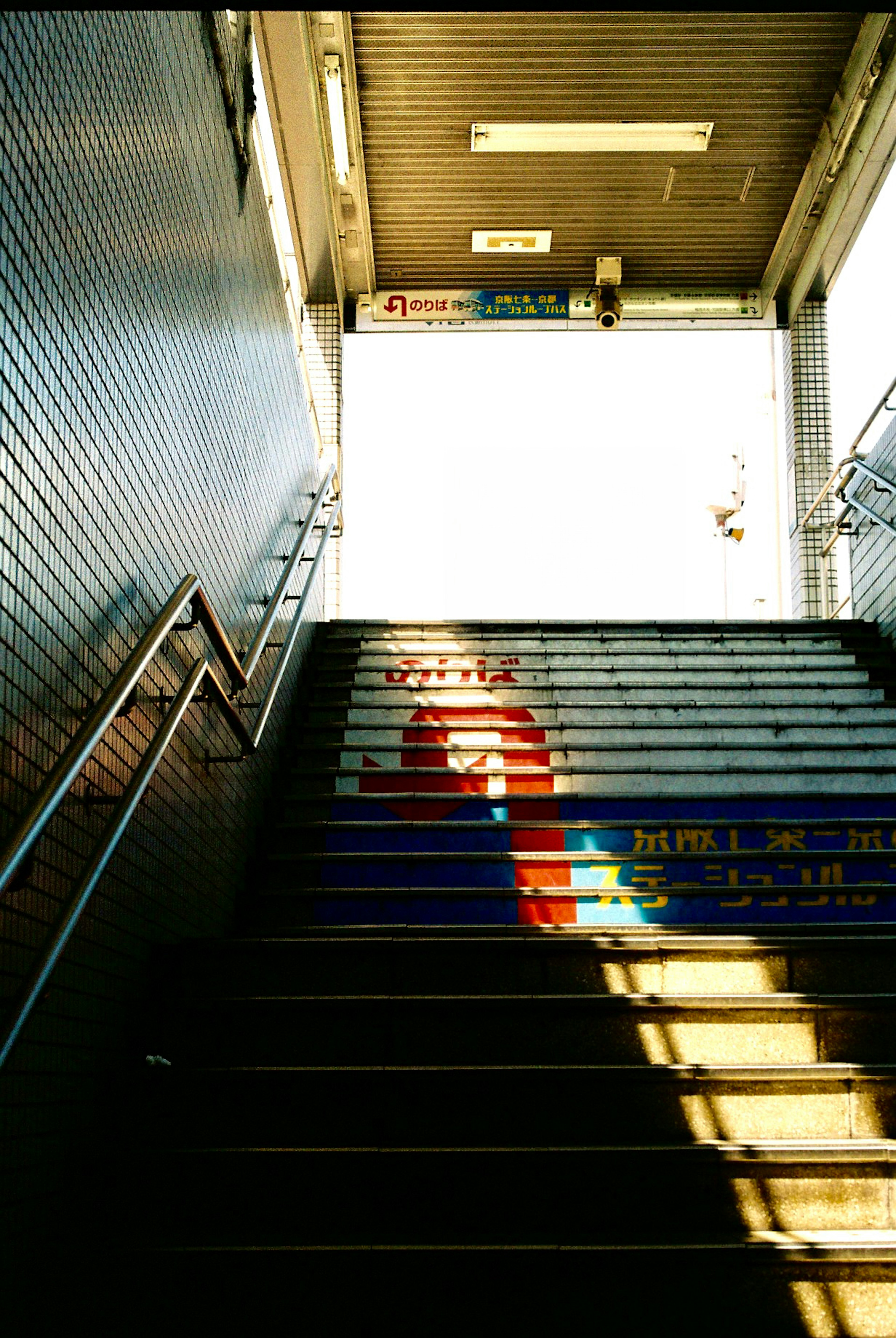 Sombra de una persona subiendo escaleras coloridas con luz brillante en la parte superior