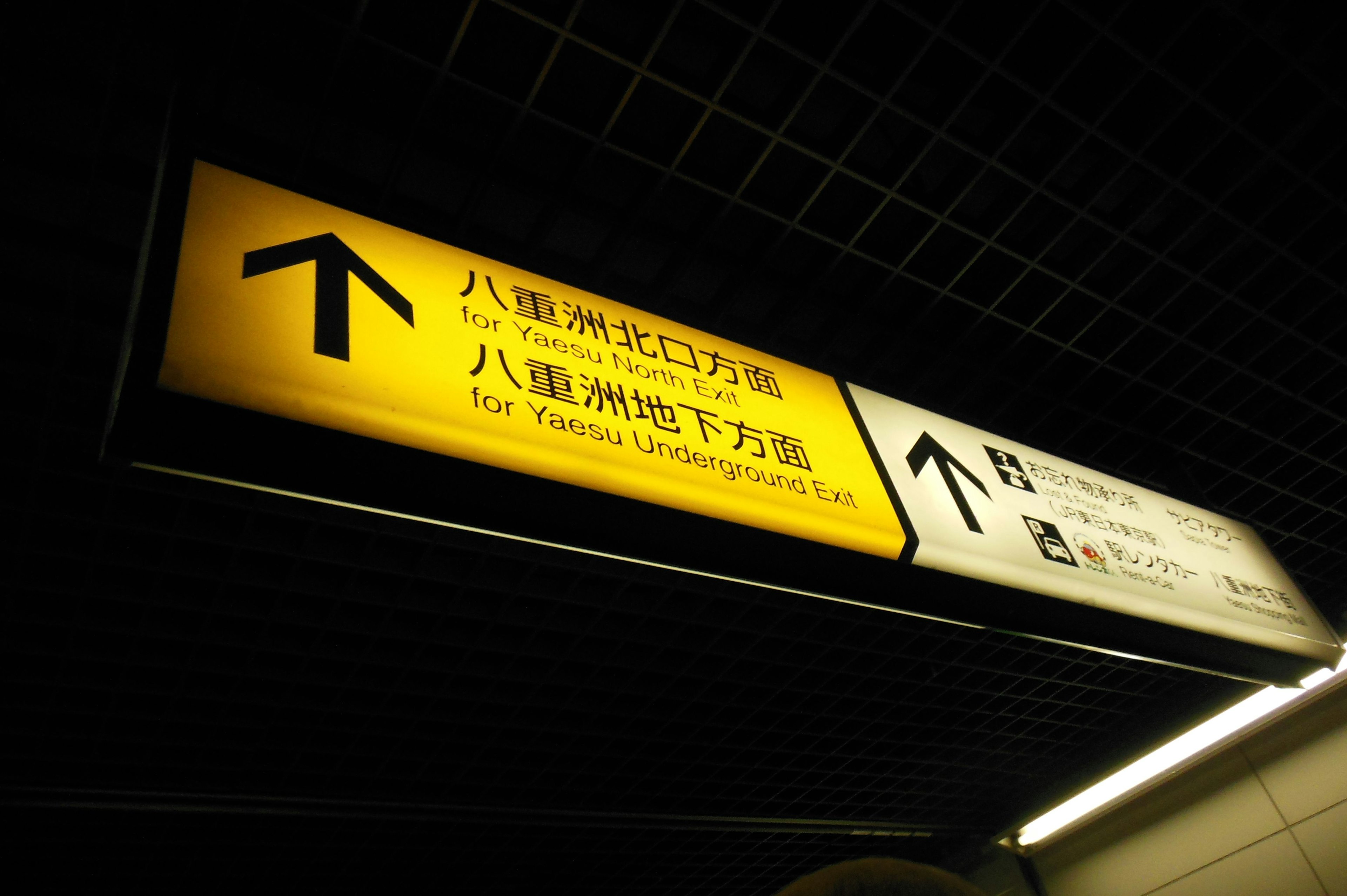 Subway station directional sign with yellow arrow and text