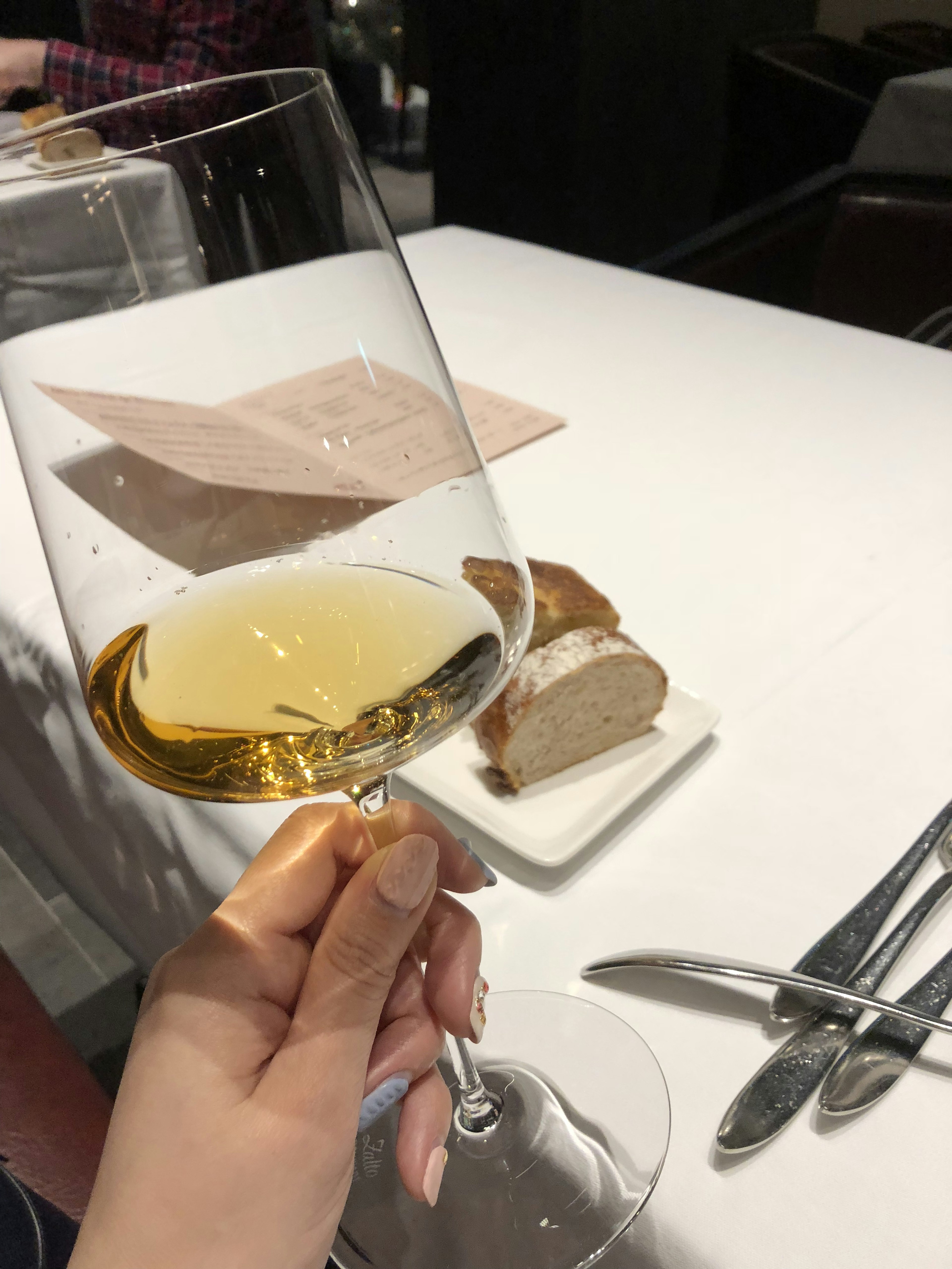 Eine Hand, die ein Glas Weißwein mit einem Teller Brot hält