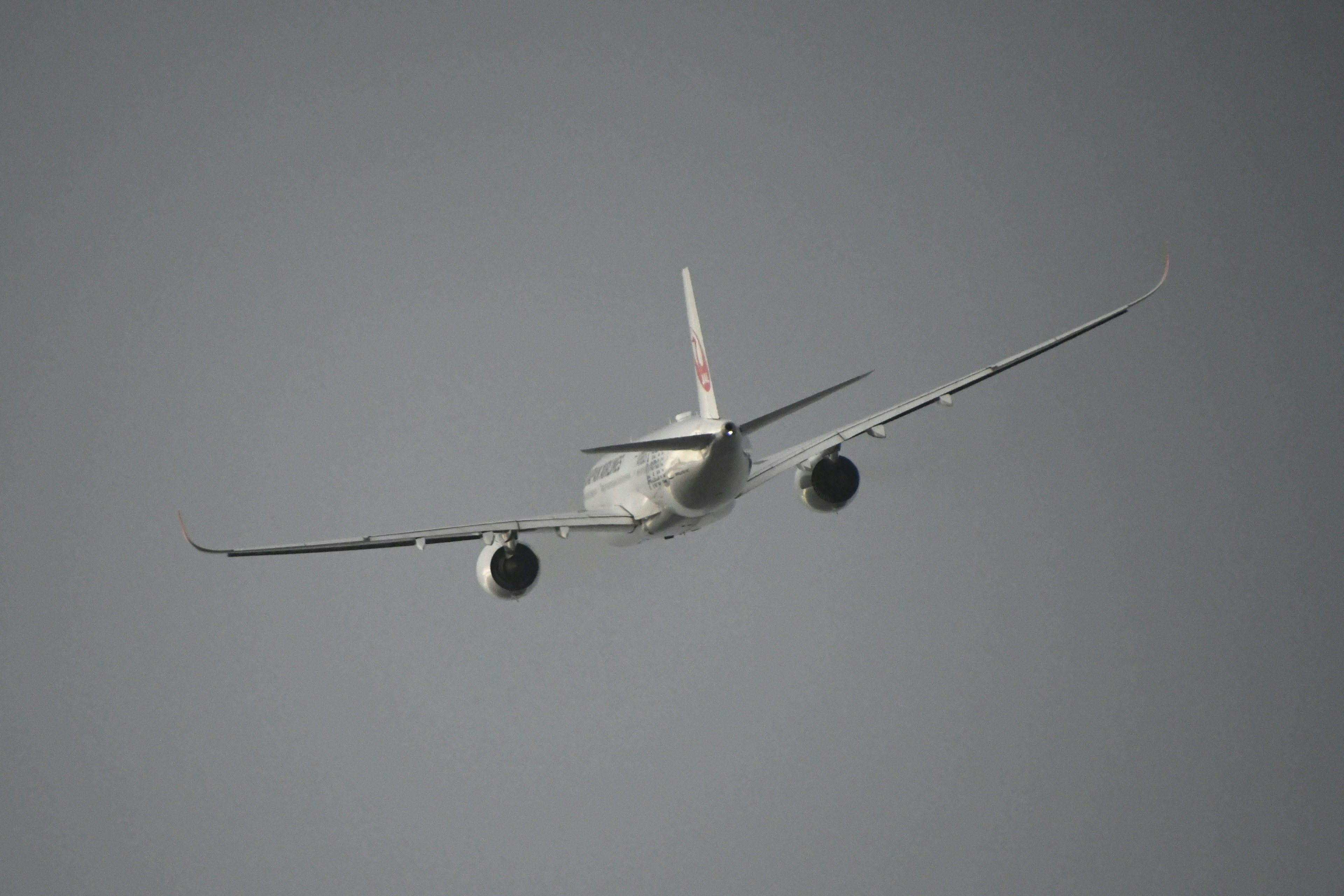 Airplane flying in the sky with a rear view showing the tail fin