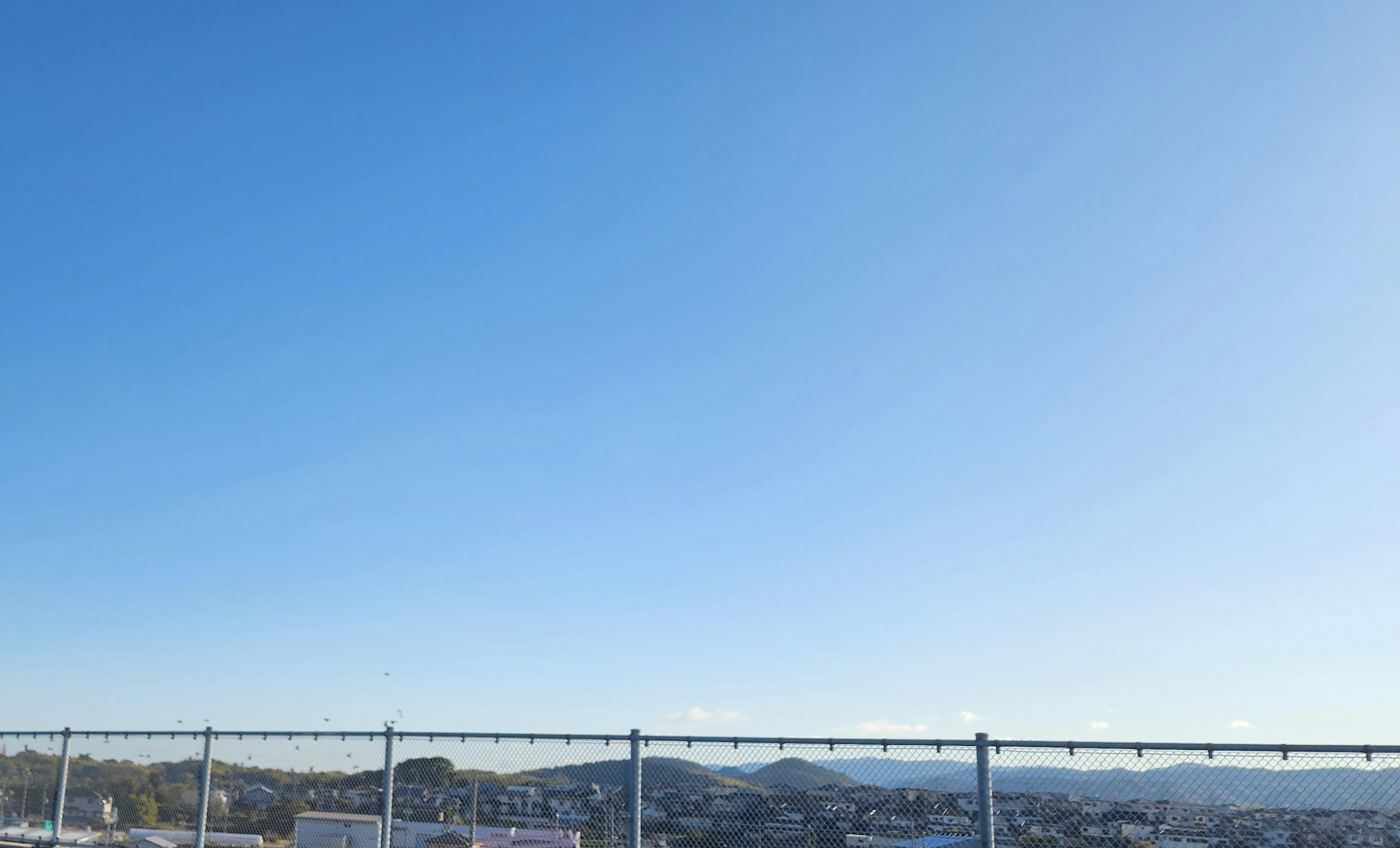 Clear blue sky with a fence in the foreground