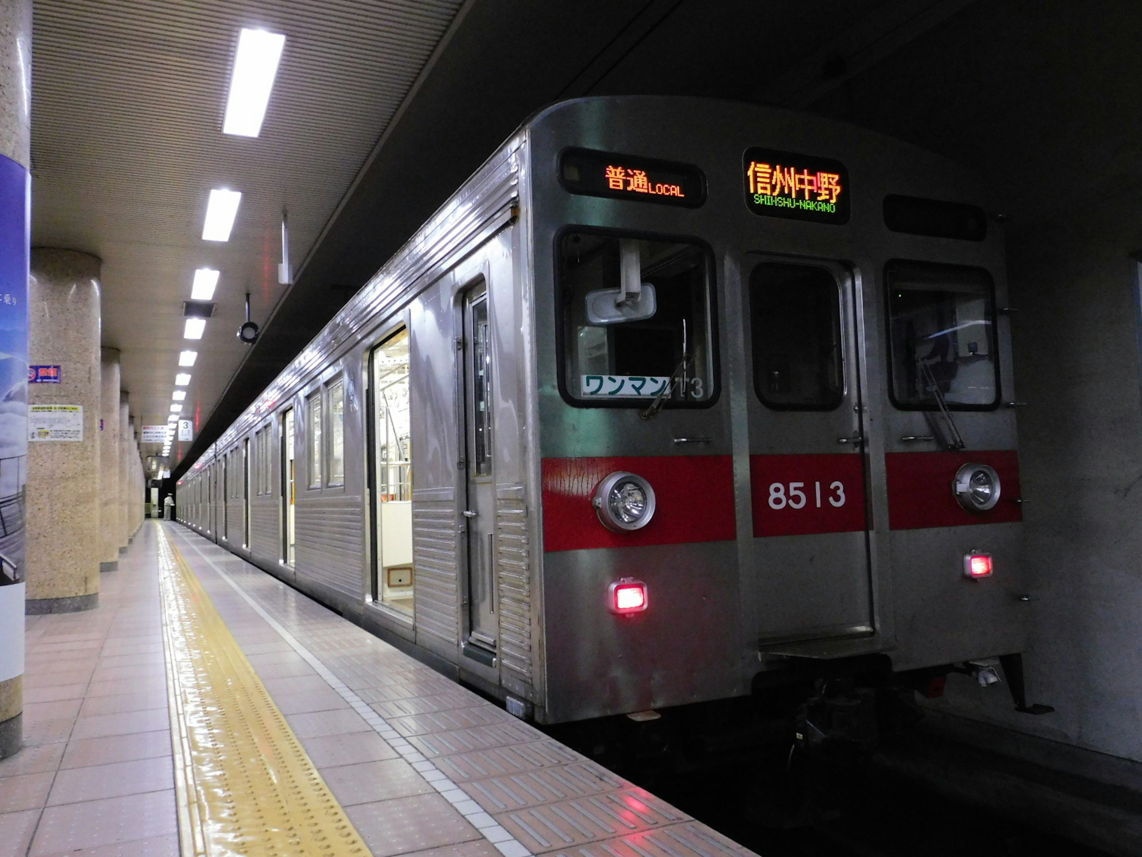 Silver subway train with red stripe at a station