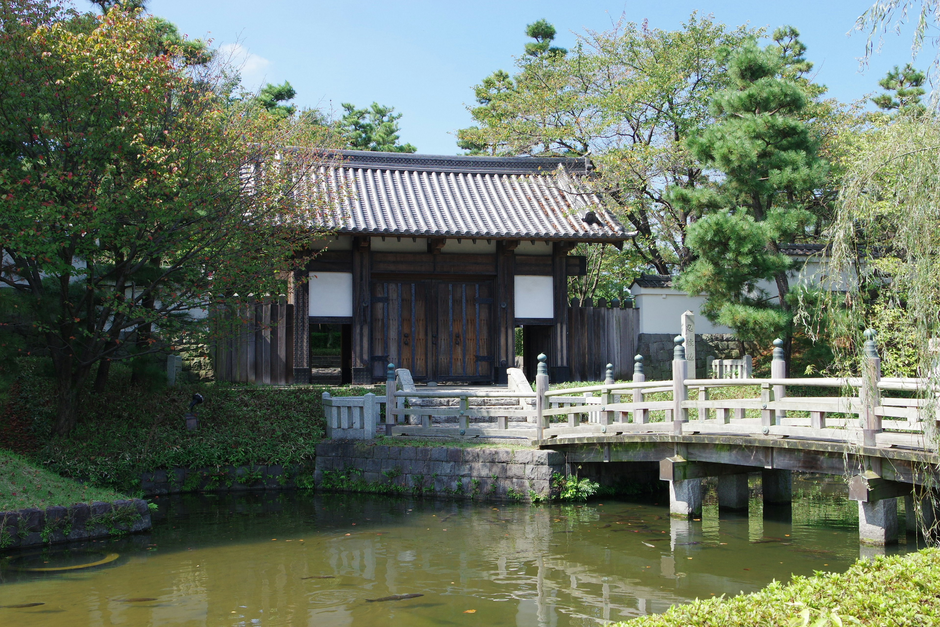 Scenic view of a Japanese garden featuring a wooden bridge and traditional architecture