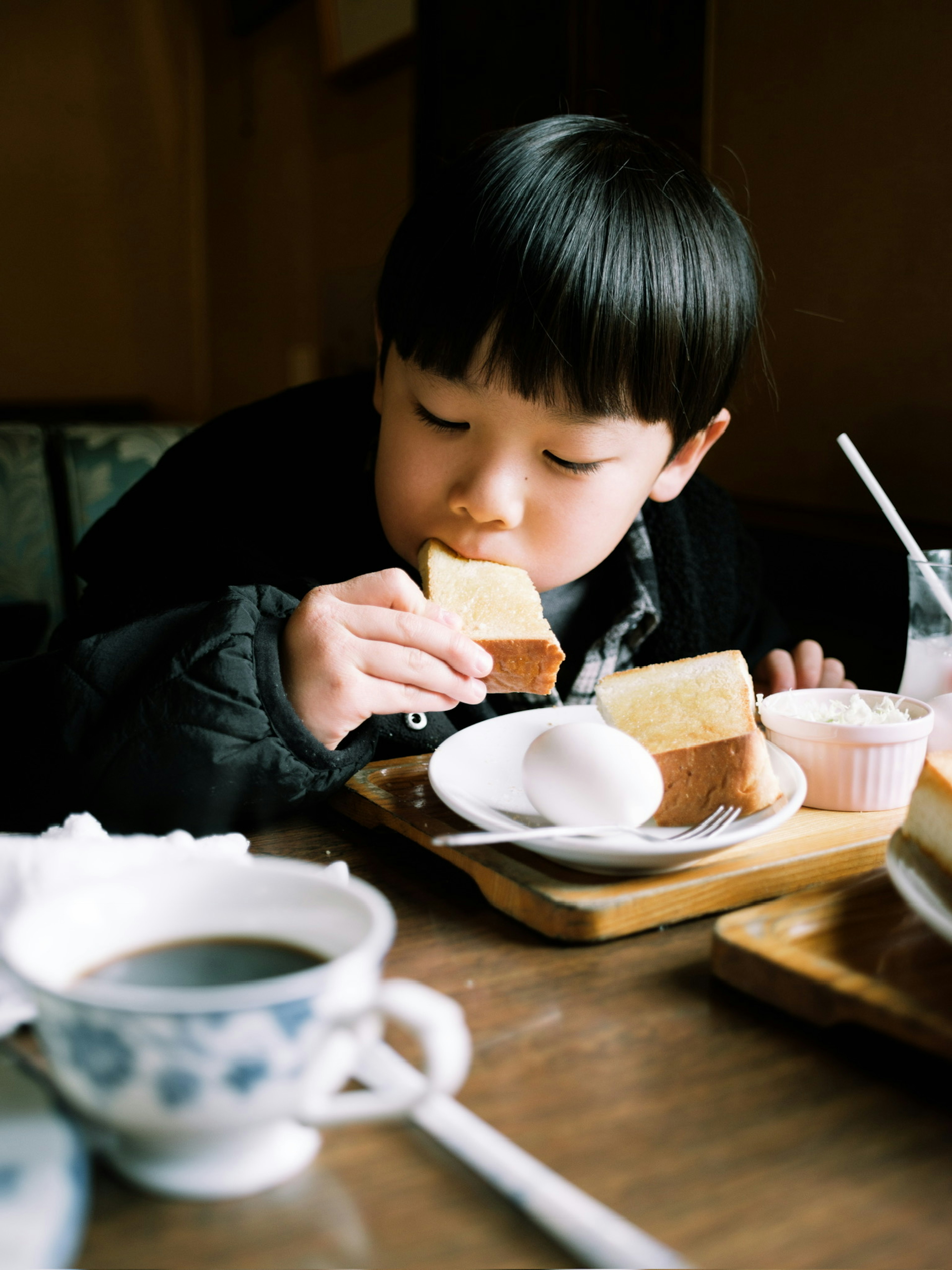 Un enfant dégustant une part de gâteau dans un café confortable