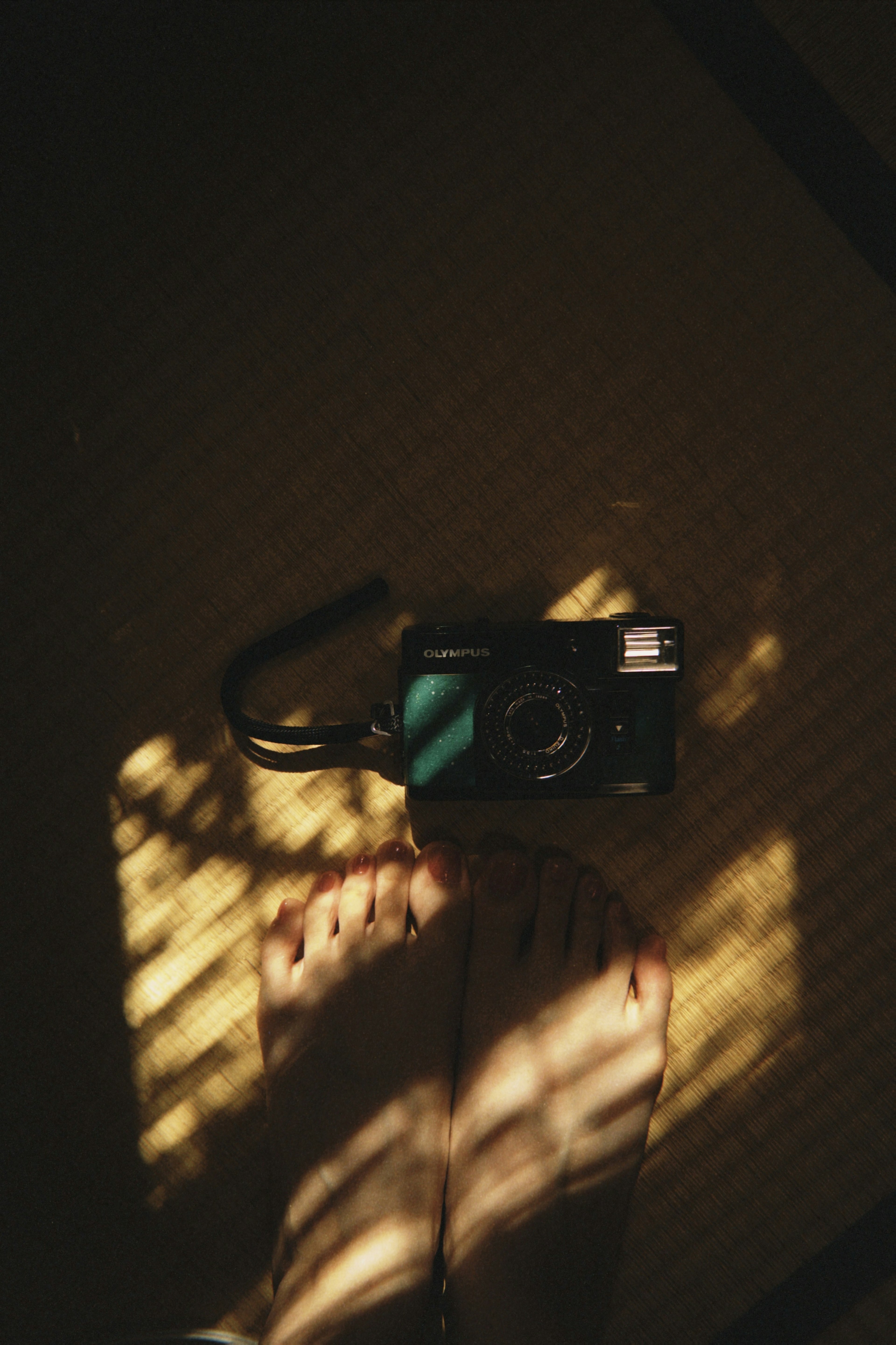 A photo of a camera and feet with beautiful contrast of light and shadow