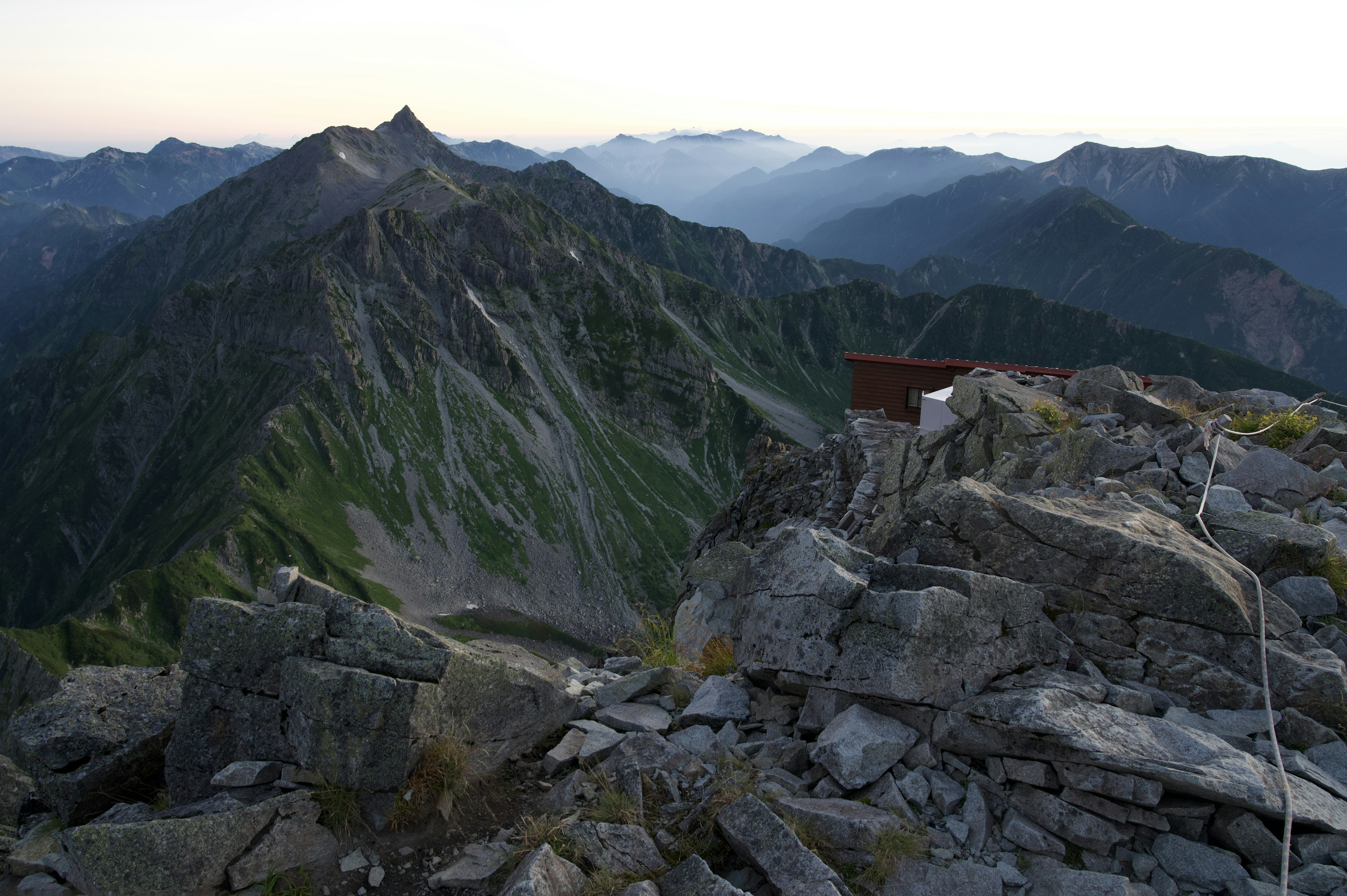 View from the mountain summit featuring rocky terrain and green slopes