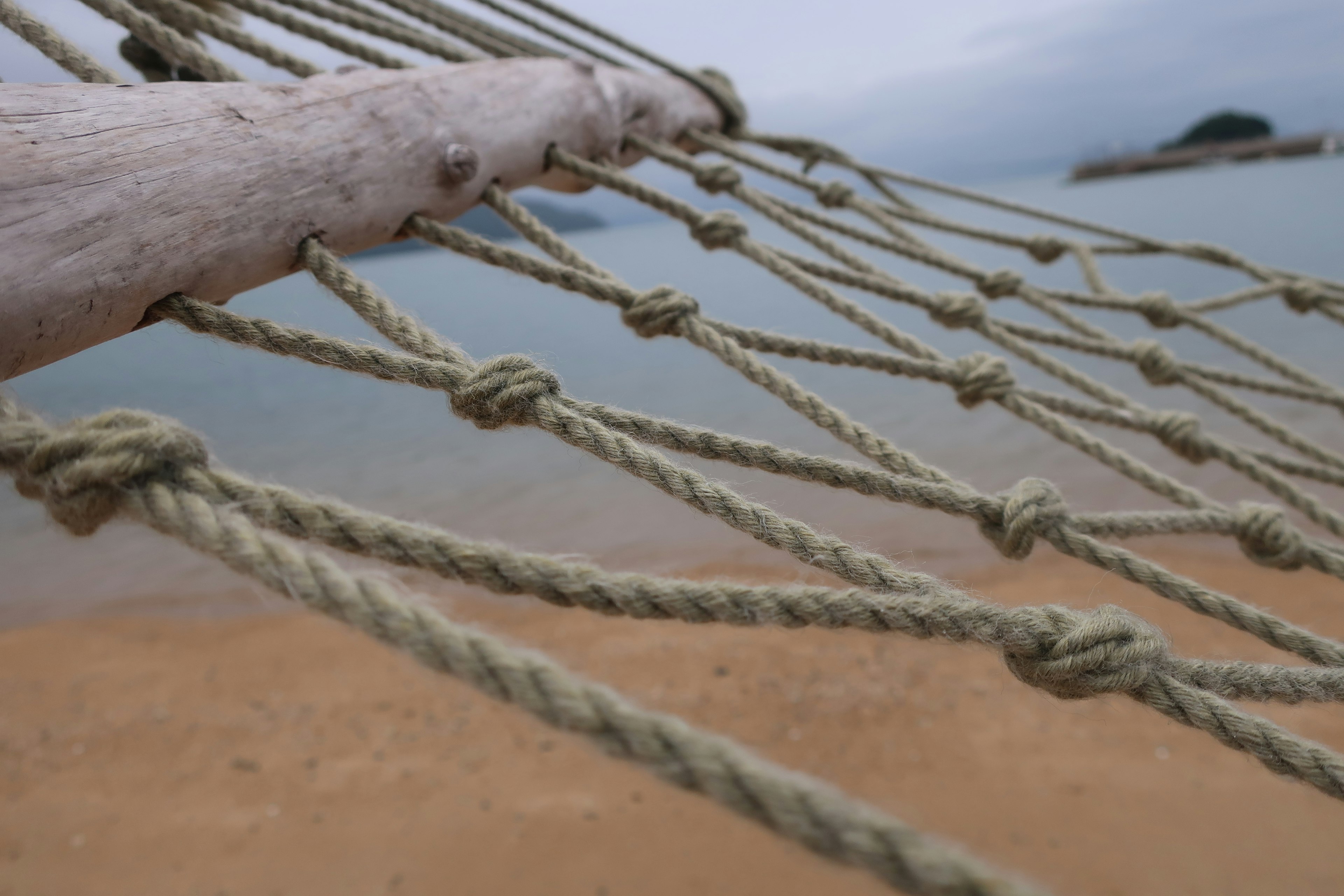 Rete di corda vicino alla spiaggia con un mare tranquillo sullo sfondo