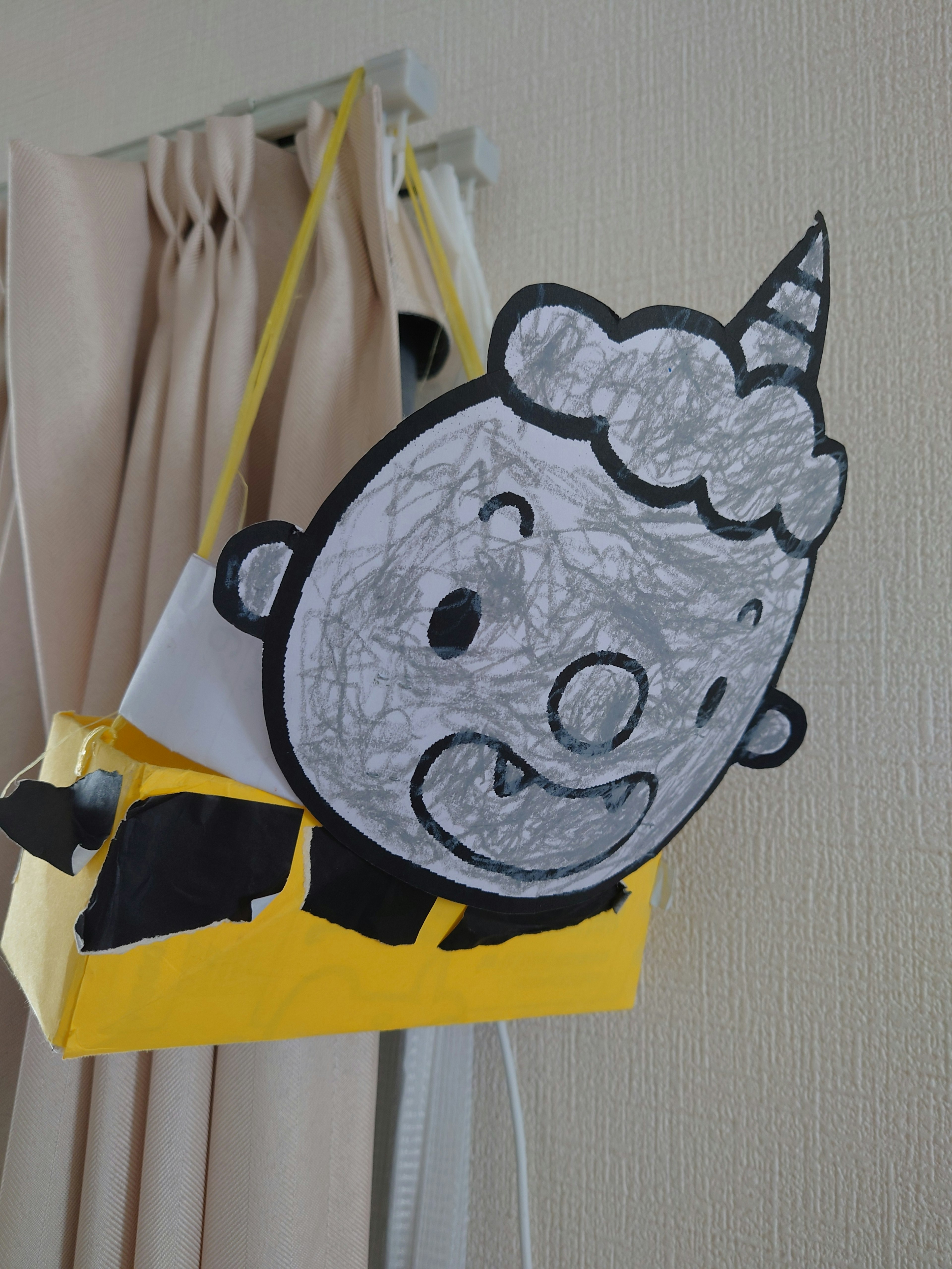 Un visage de personnage dessiné sur un sac jaune avec des traits ludiques