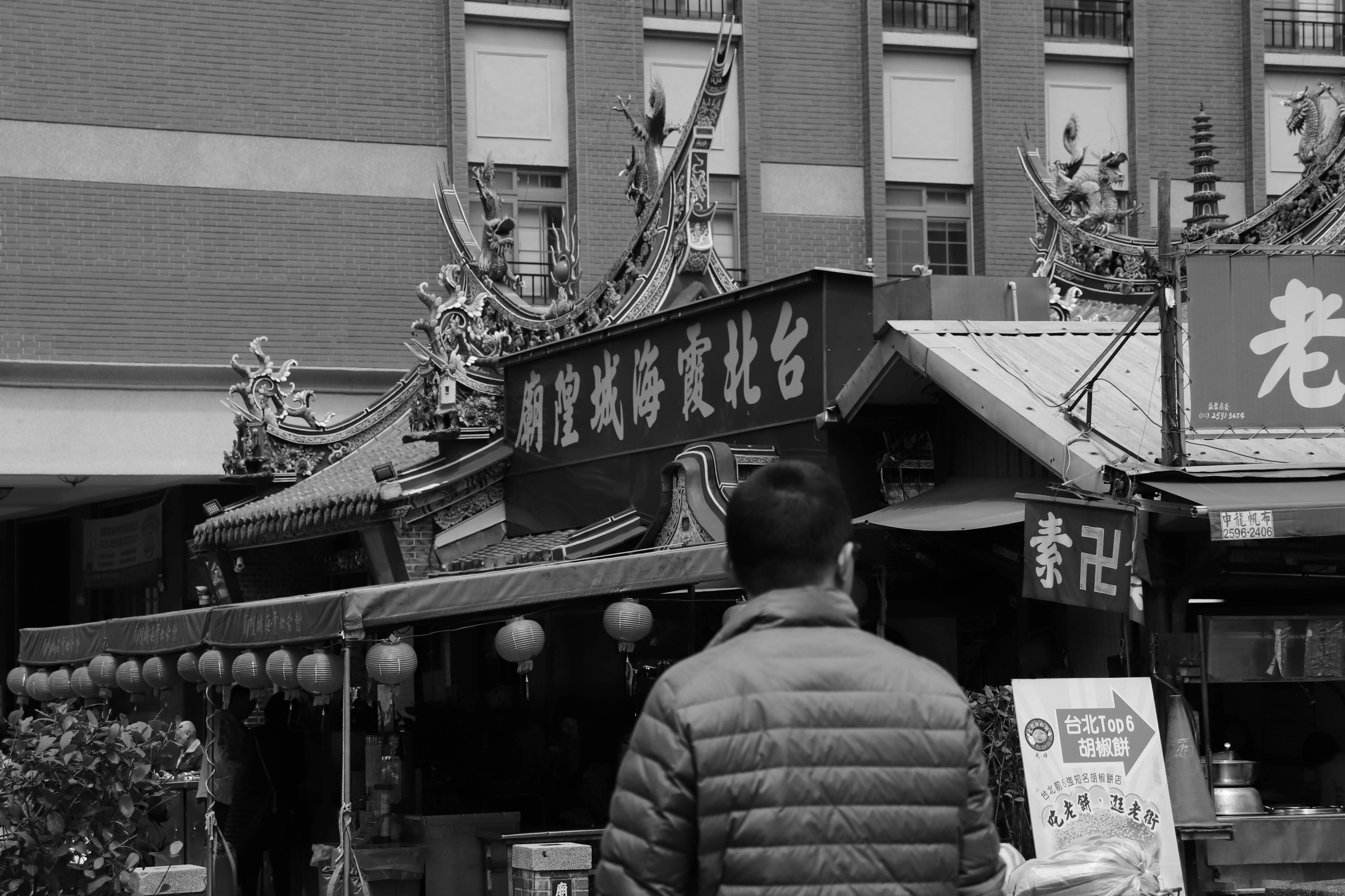 Uomo che guarda un chiosco di cibo in bianco e nero in una strada di mercato tradizionale