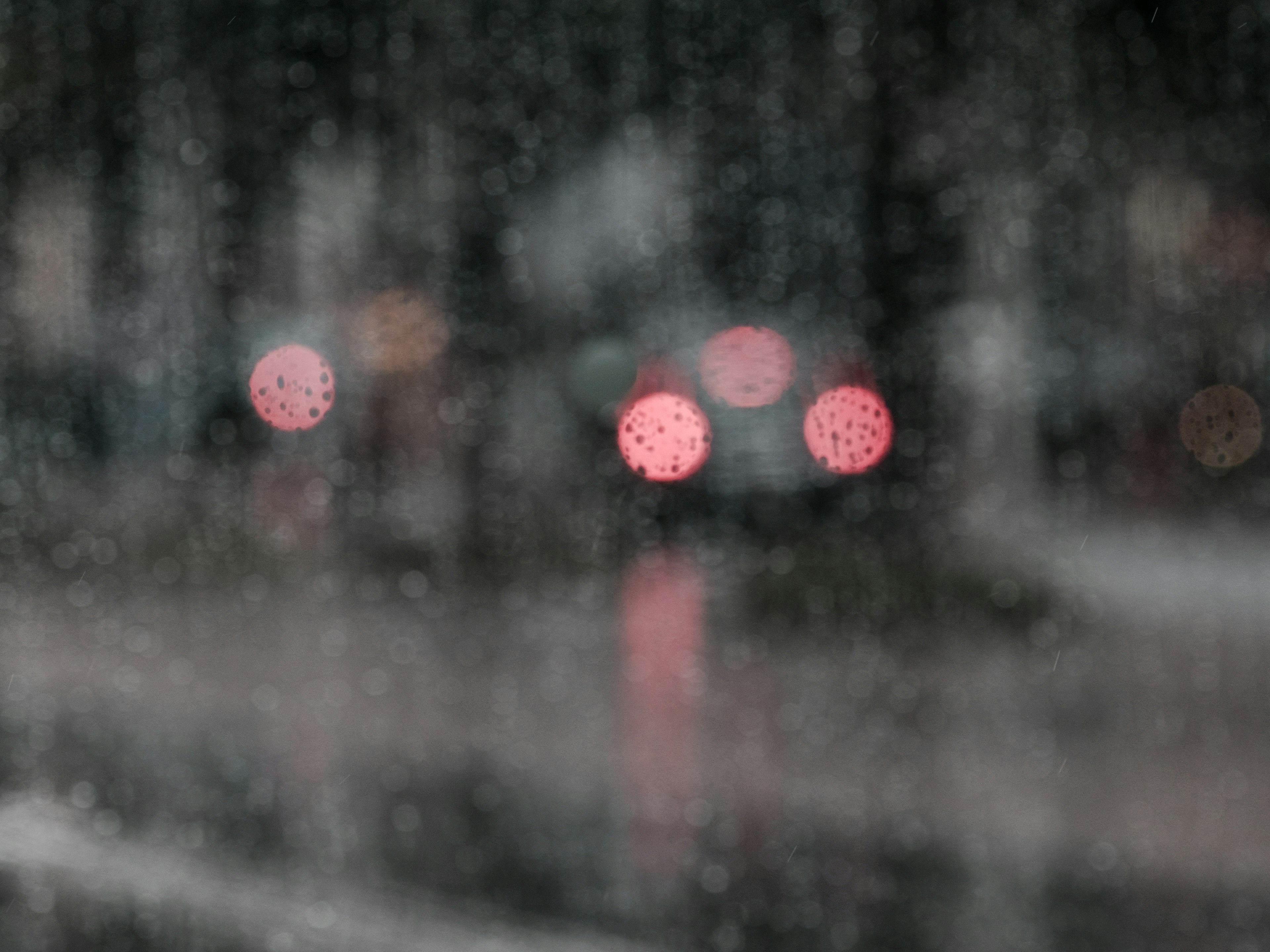 雨の中のぼやけた赤い光と湿った窓