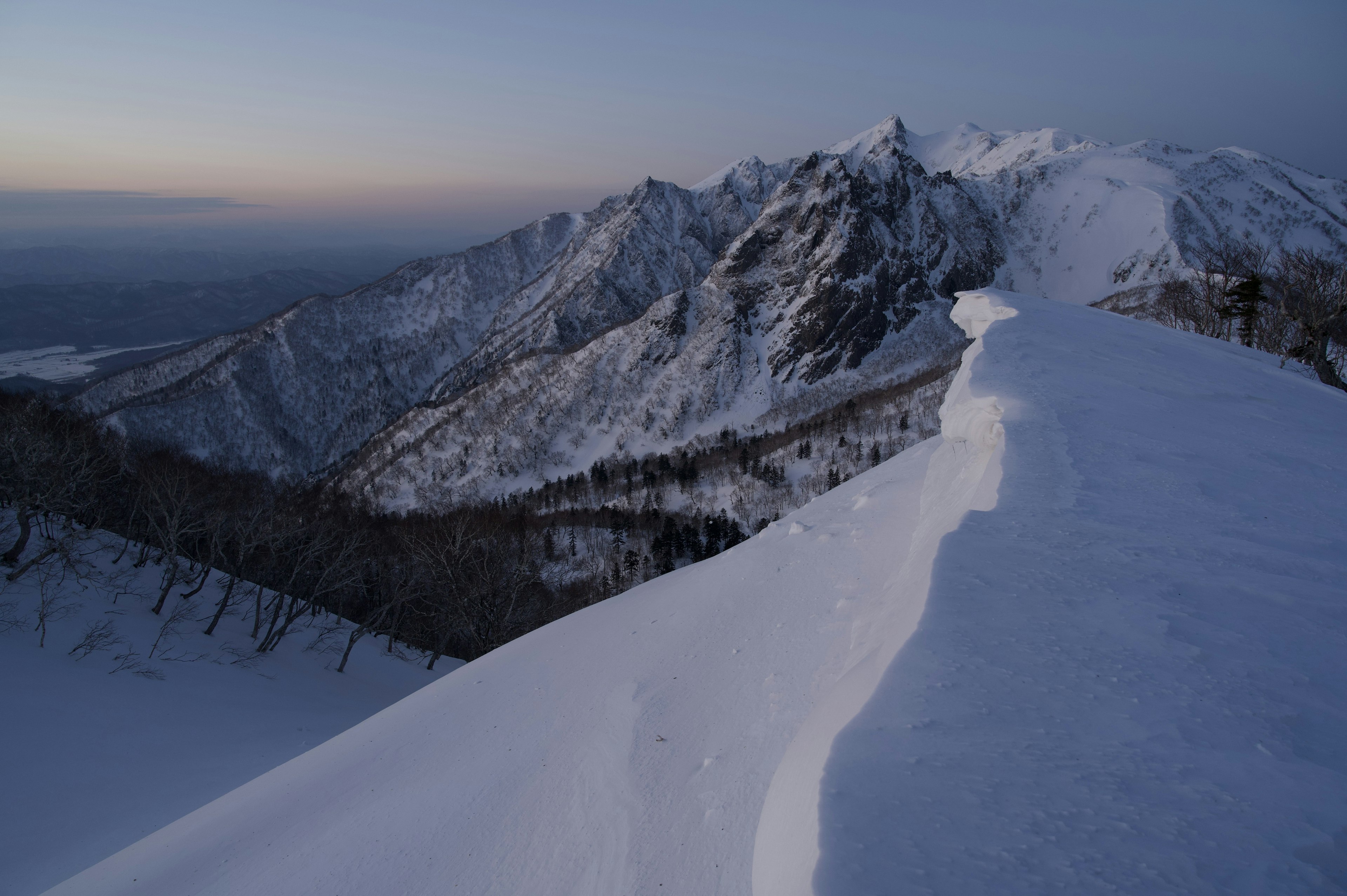 Paisaje montañoso cubierto de nieve con un crepúsculo sereno