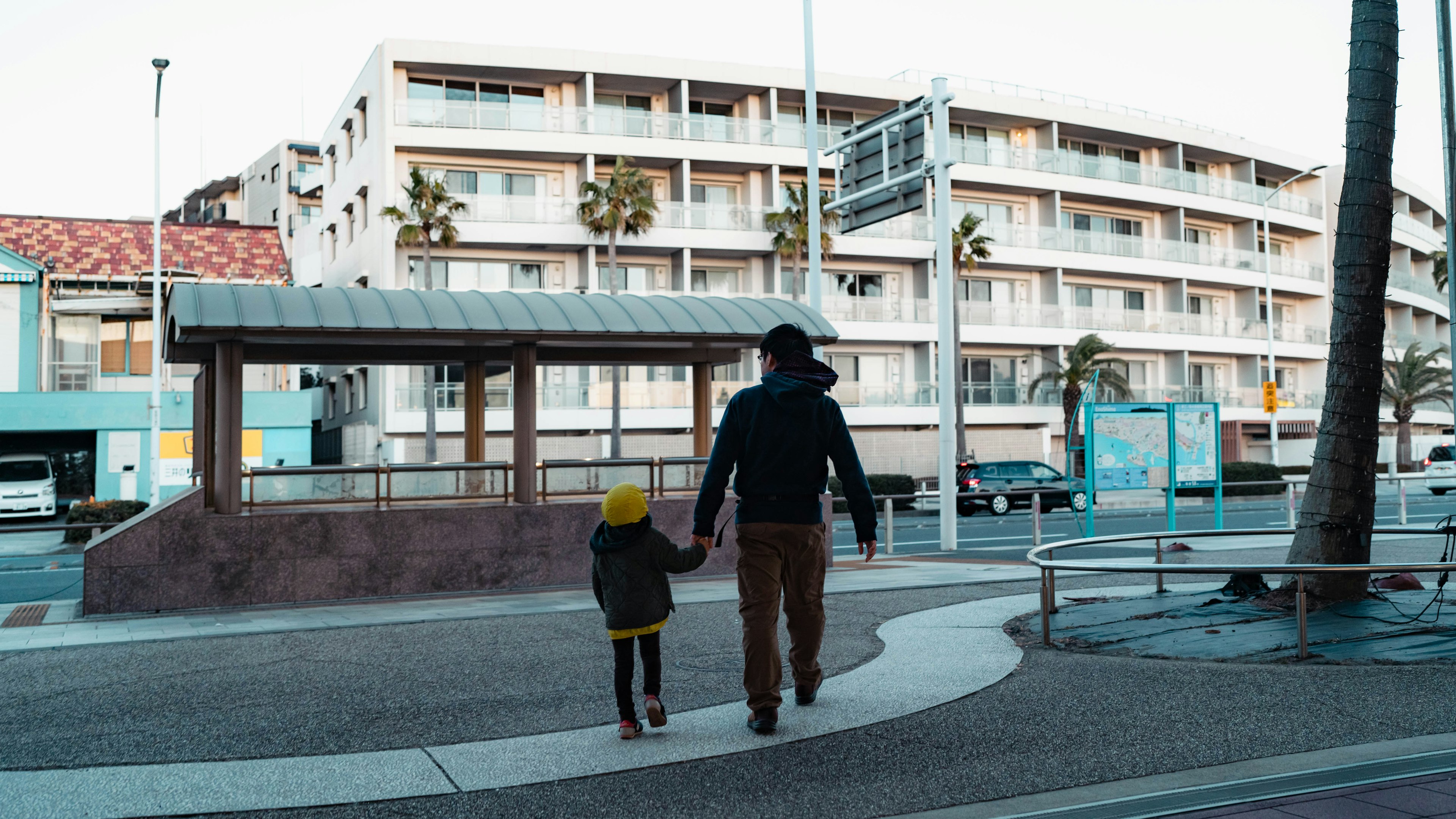 Un genitore e un bambino che camminano mano nella mano in una scena cittadina