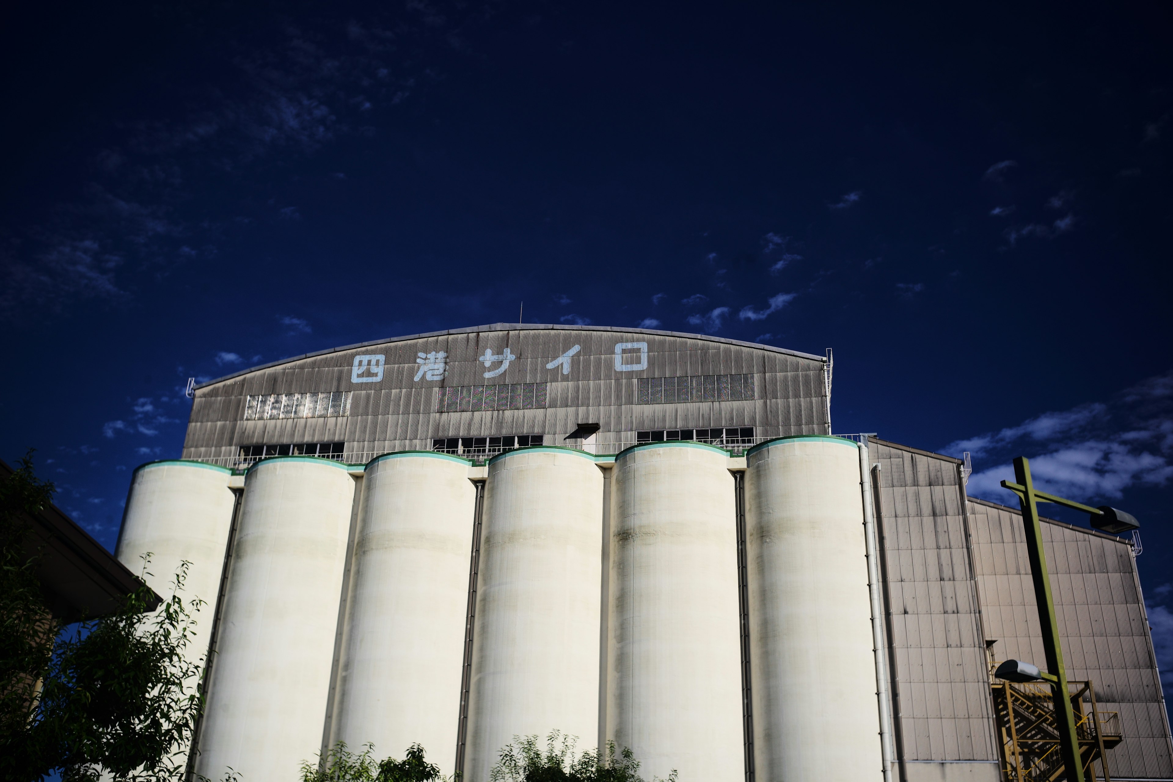 Struktur silo besar di bawah langit biru dengan silo silindris