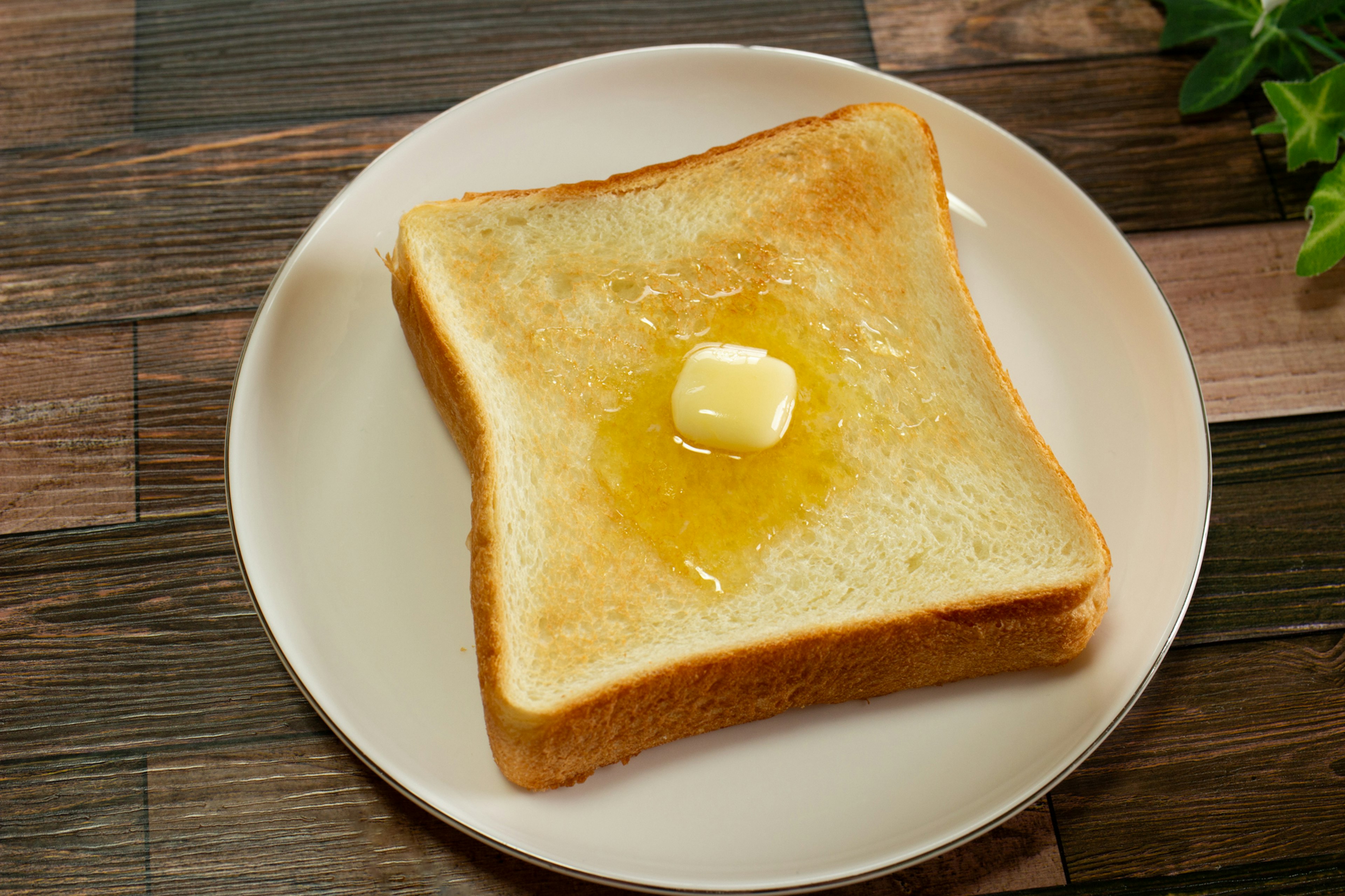 Geröstetes Brot mit Butter und Honig auf einem weißen Teller