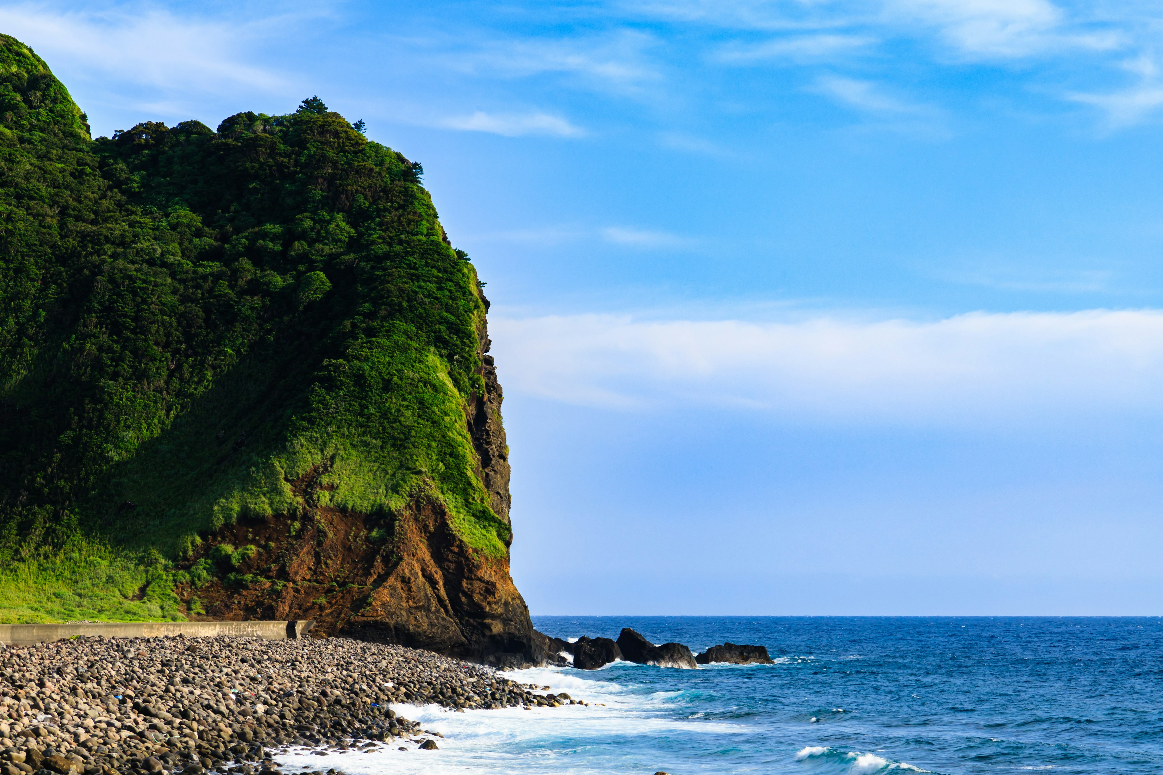 Tebing hijau subur dengan pemandangan laut biru