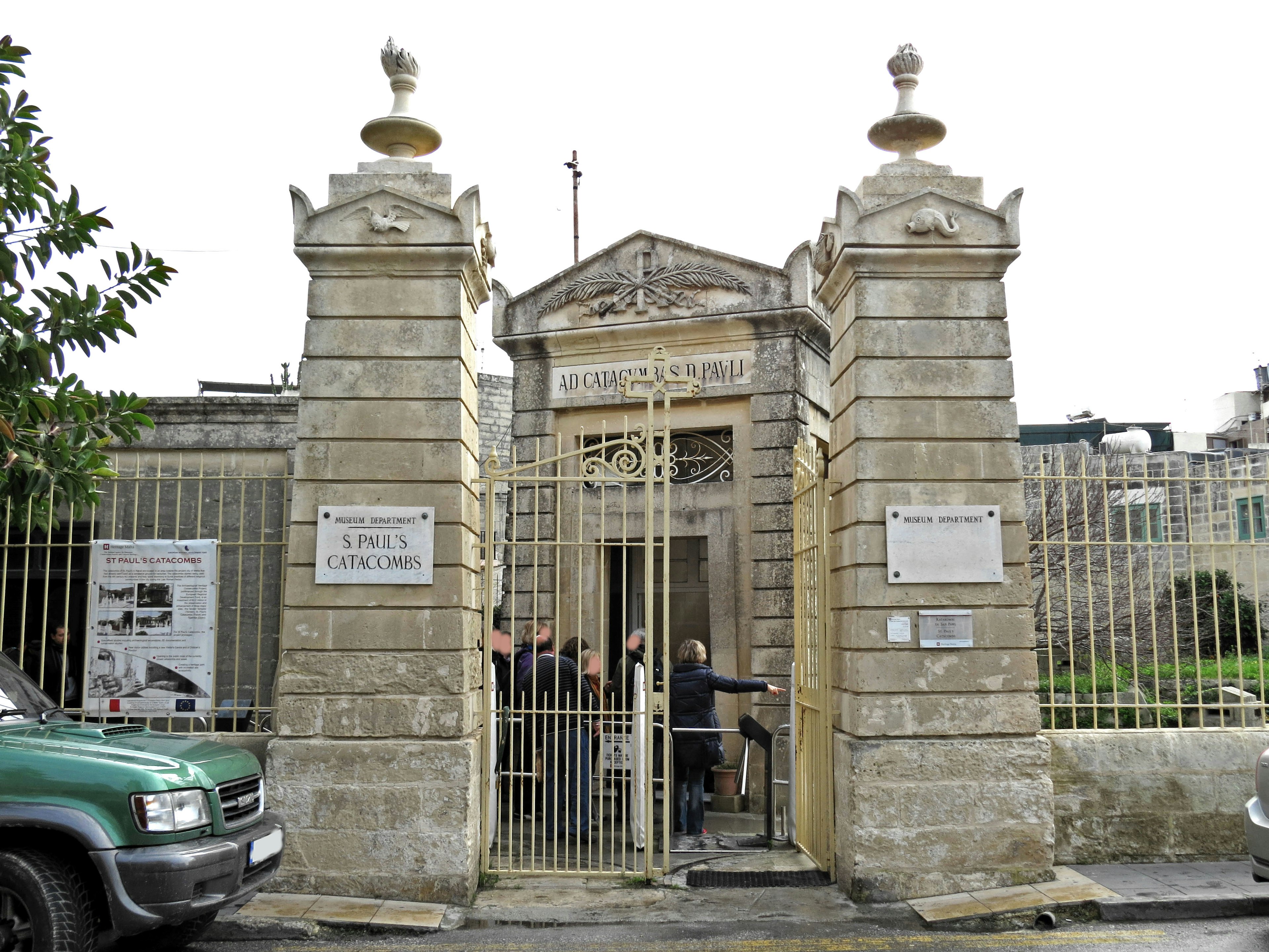 Entrance of a stone building with a metal gate and people entering