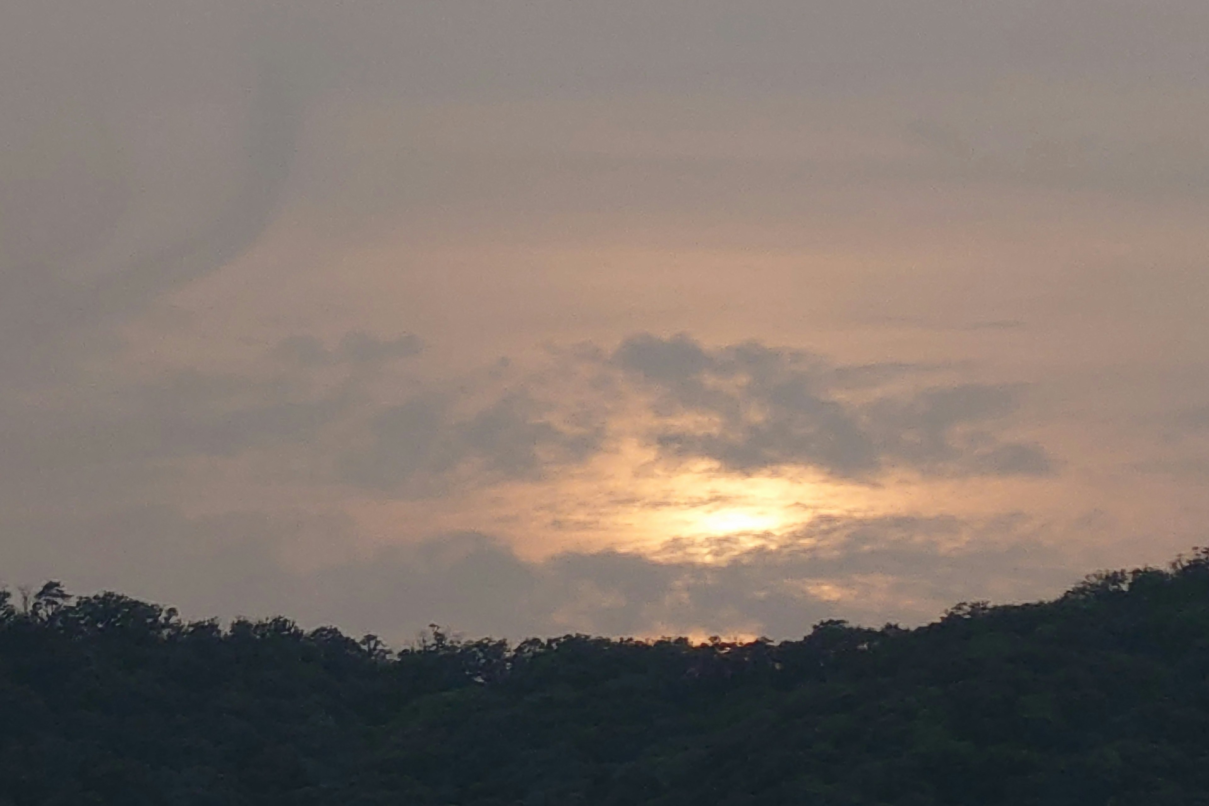 Atardecer detrás de nubes sobre la silueta de una montaña