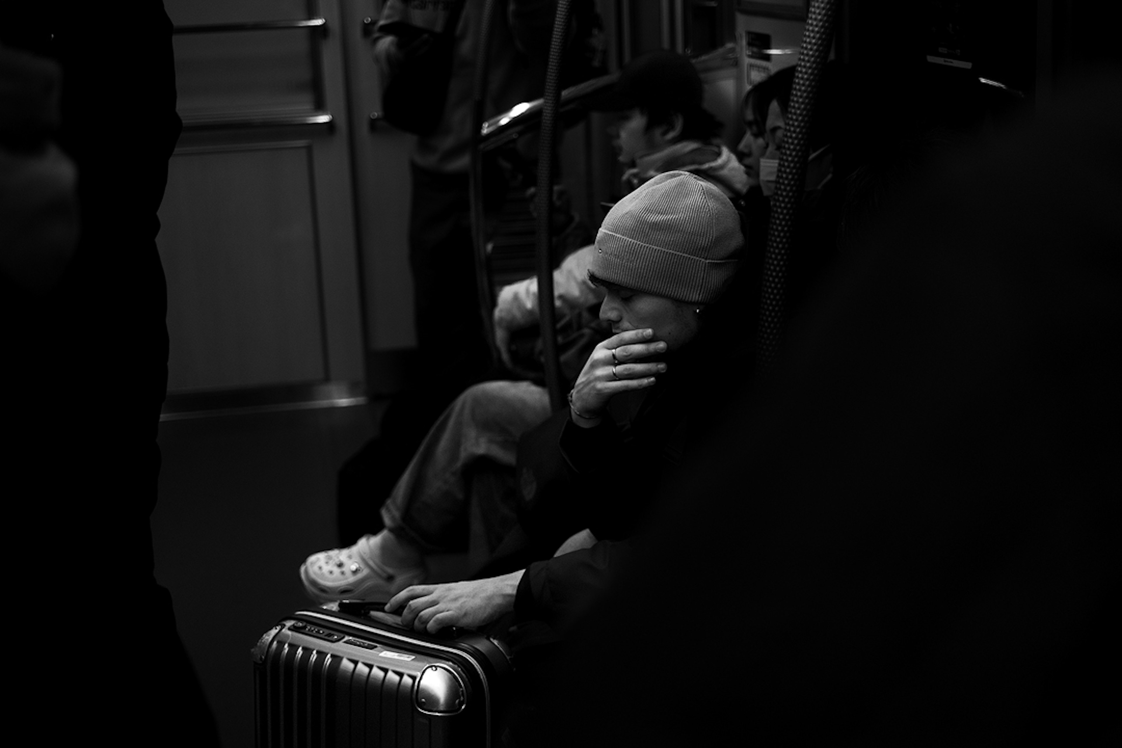 Kind sitzt auf Gepäck in der U-Bahn umgeben von Pendlern