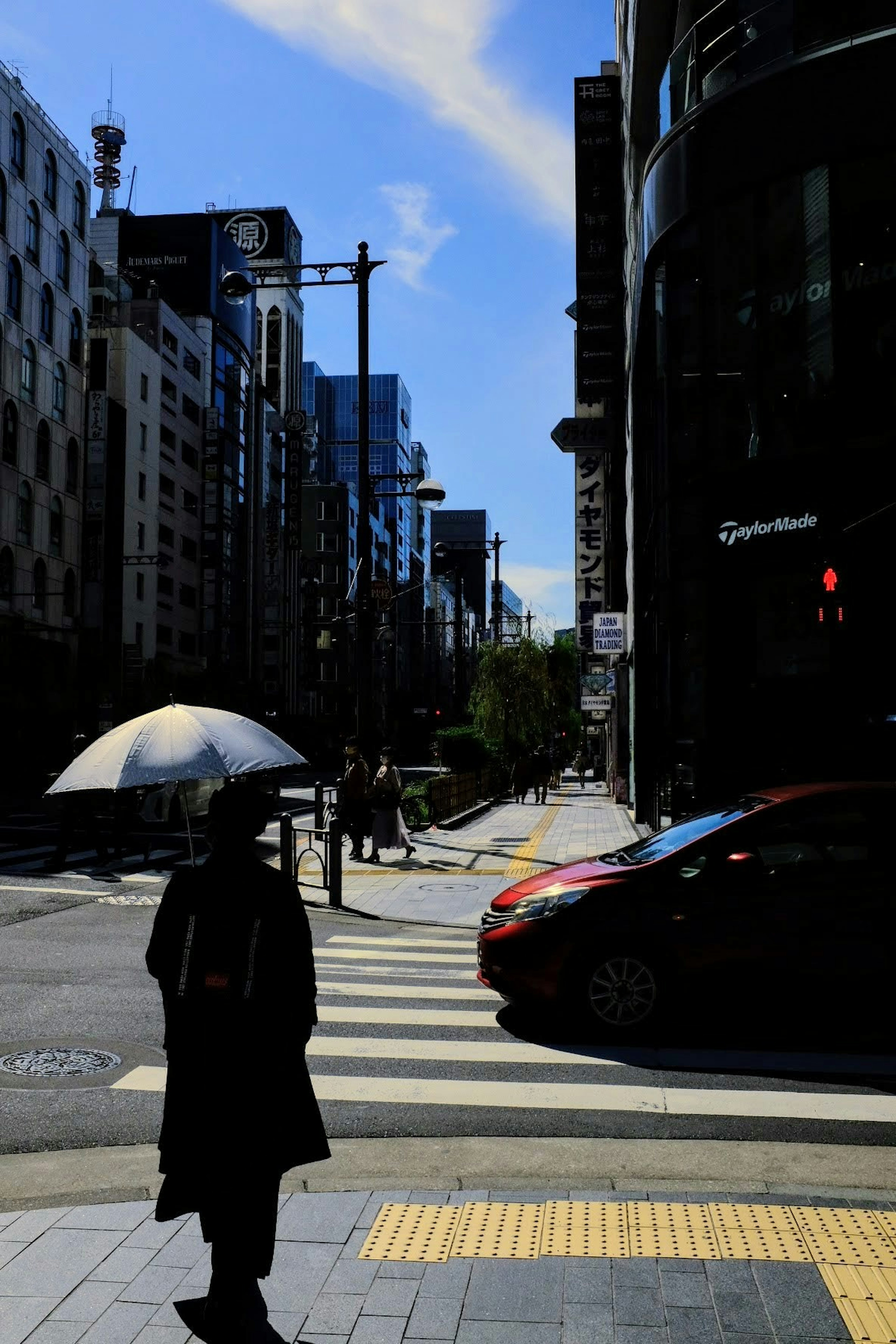 Person crossing the street with an umbrella and city buildings in the background