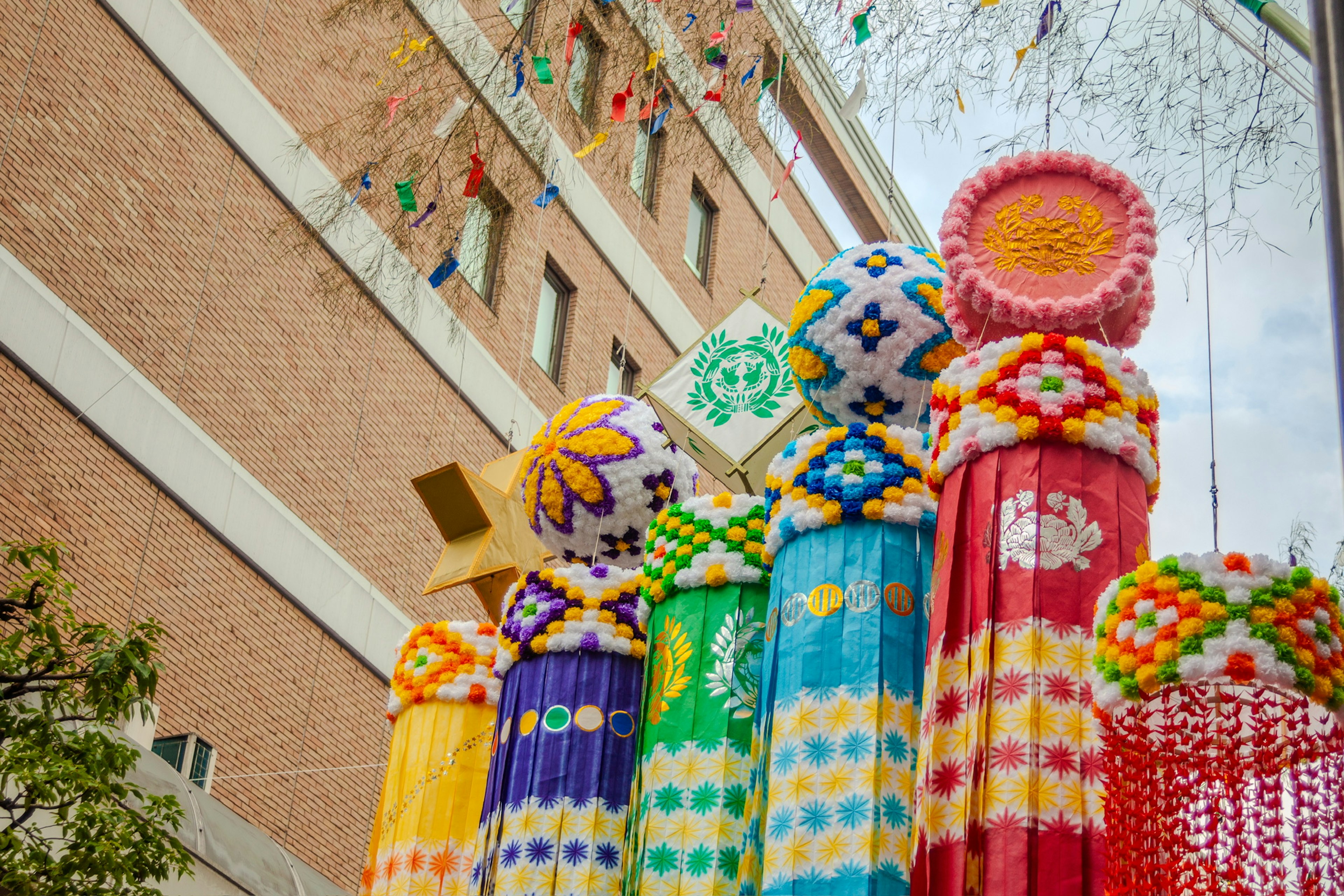 Colorful decorated pillars stand against a brick building with a cloudy sky