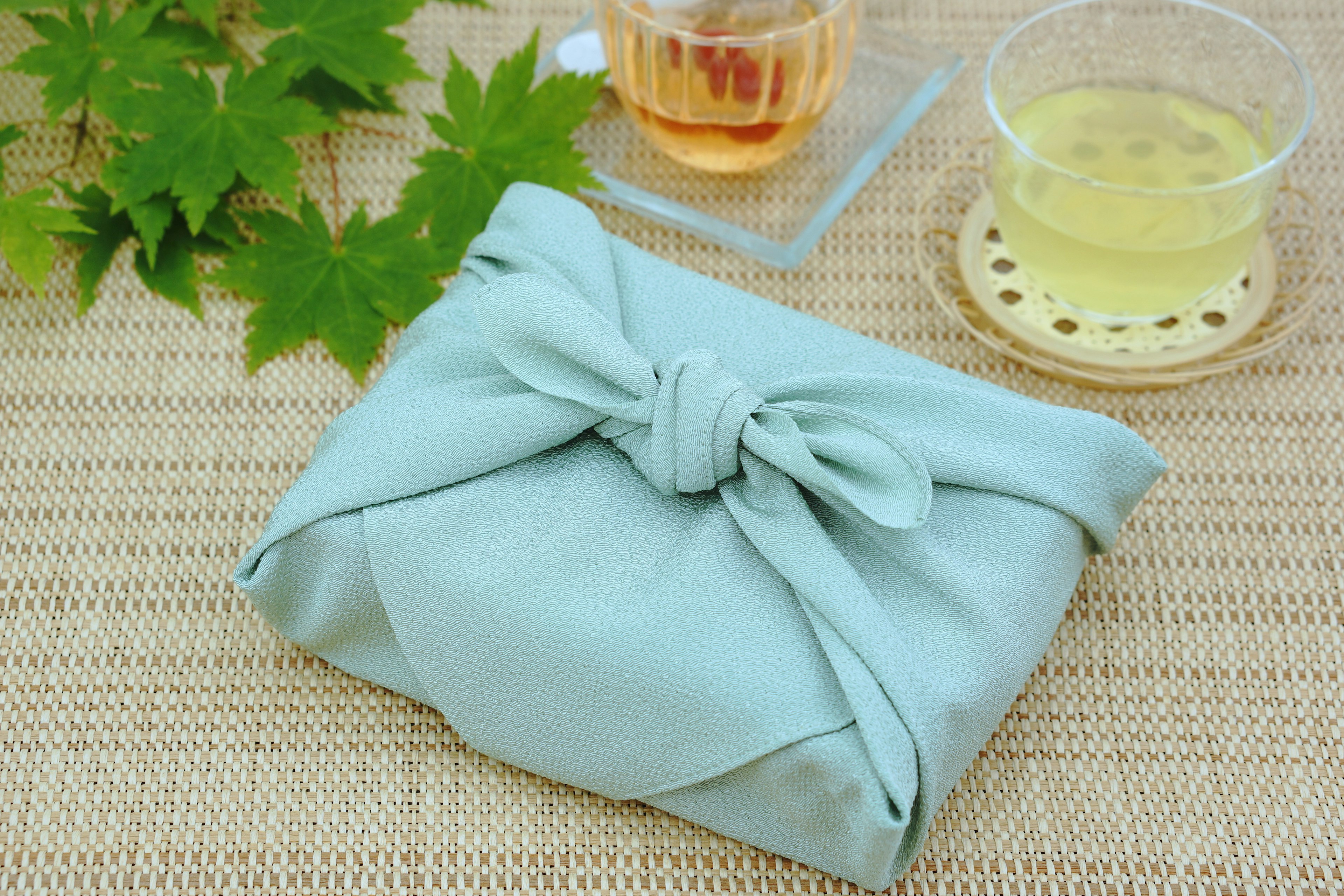 A wrapped item in blue fabric with green leaves and tea