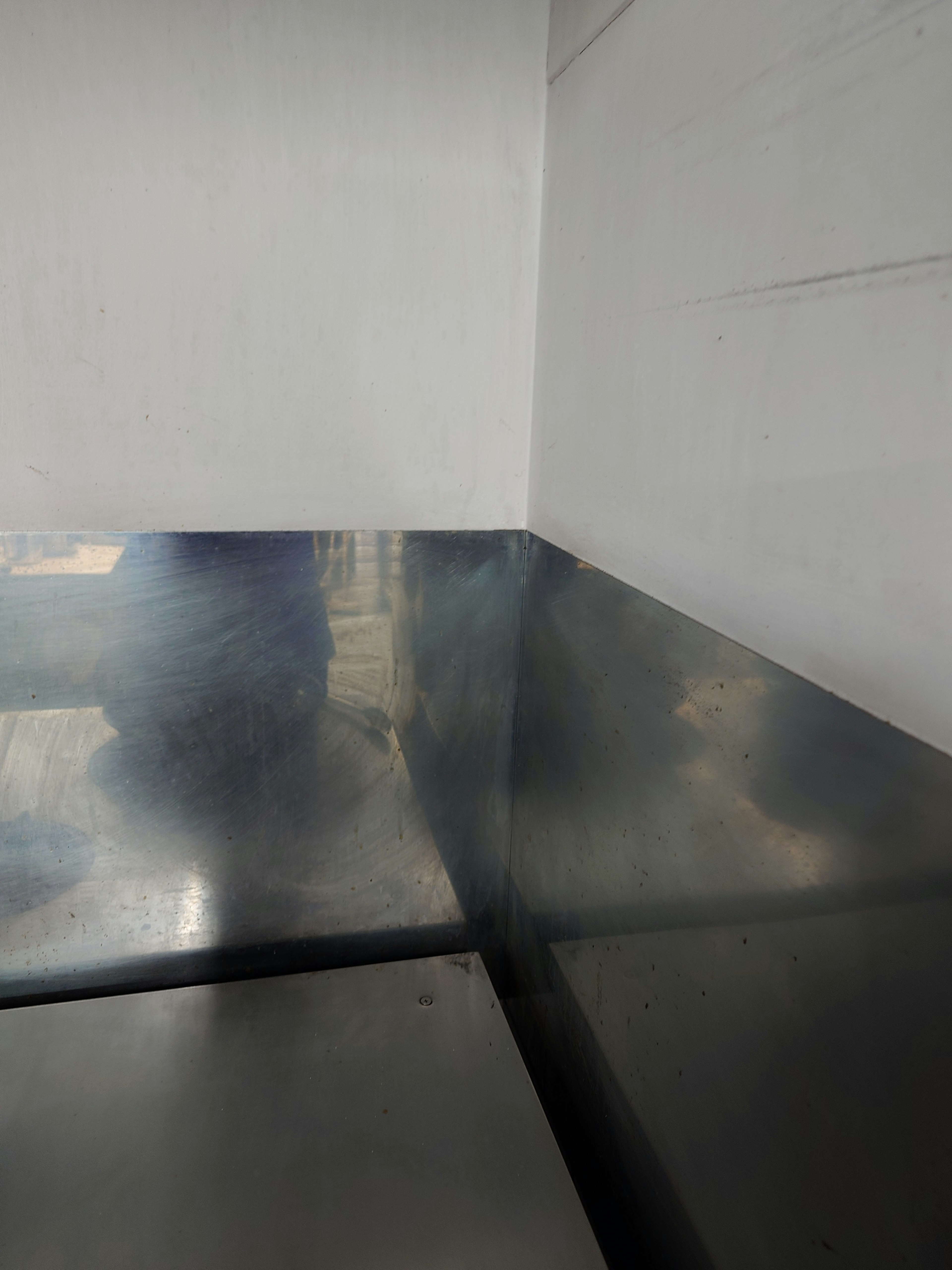 Esquina de una mesa de metal y una pared blanca