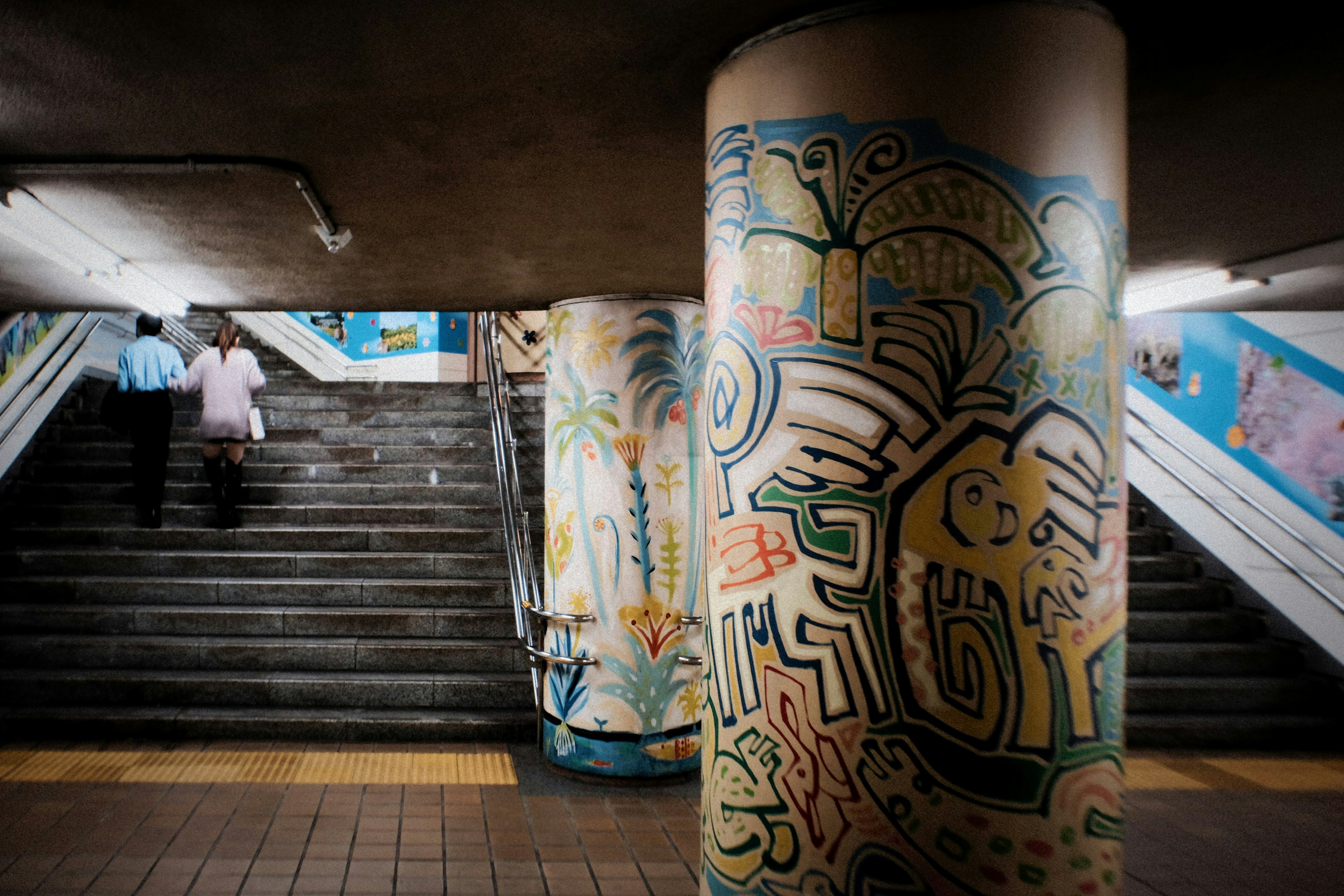 Murales coloridos y diseños de pilares en un pasaje subterráneo