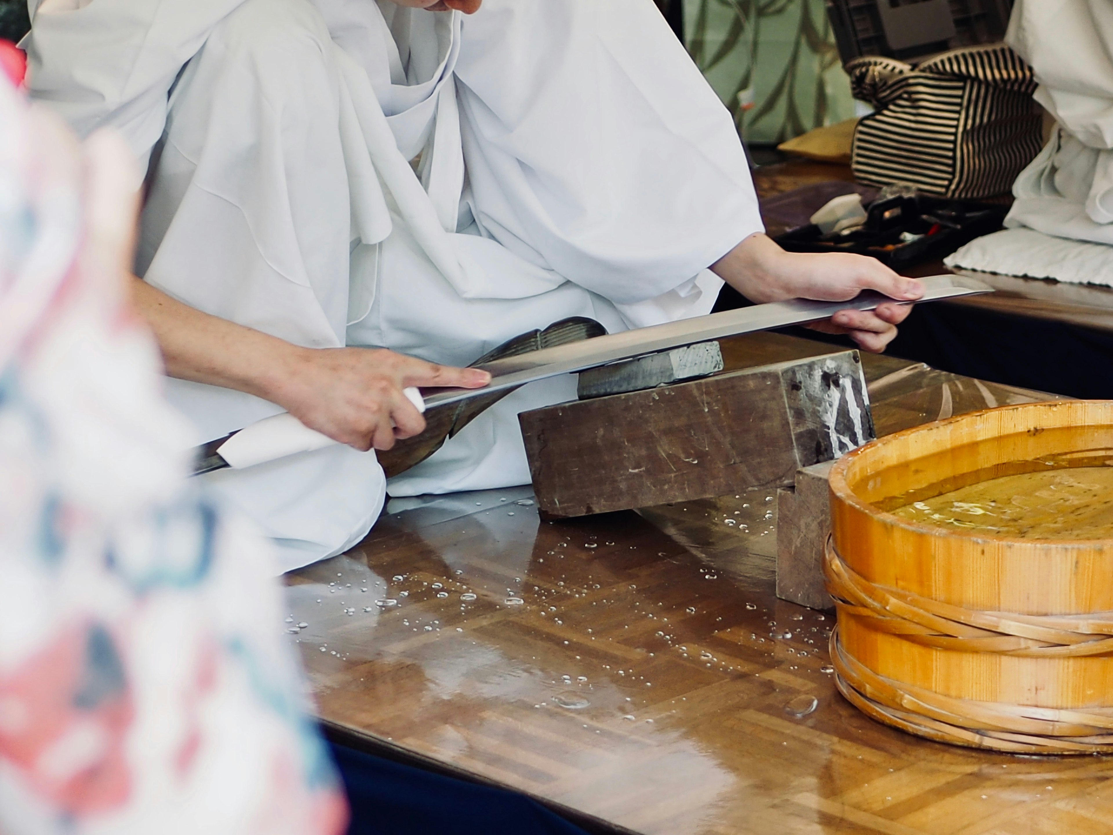 A person in a white outfit using a wooden tool for craftsmanship