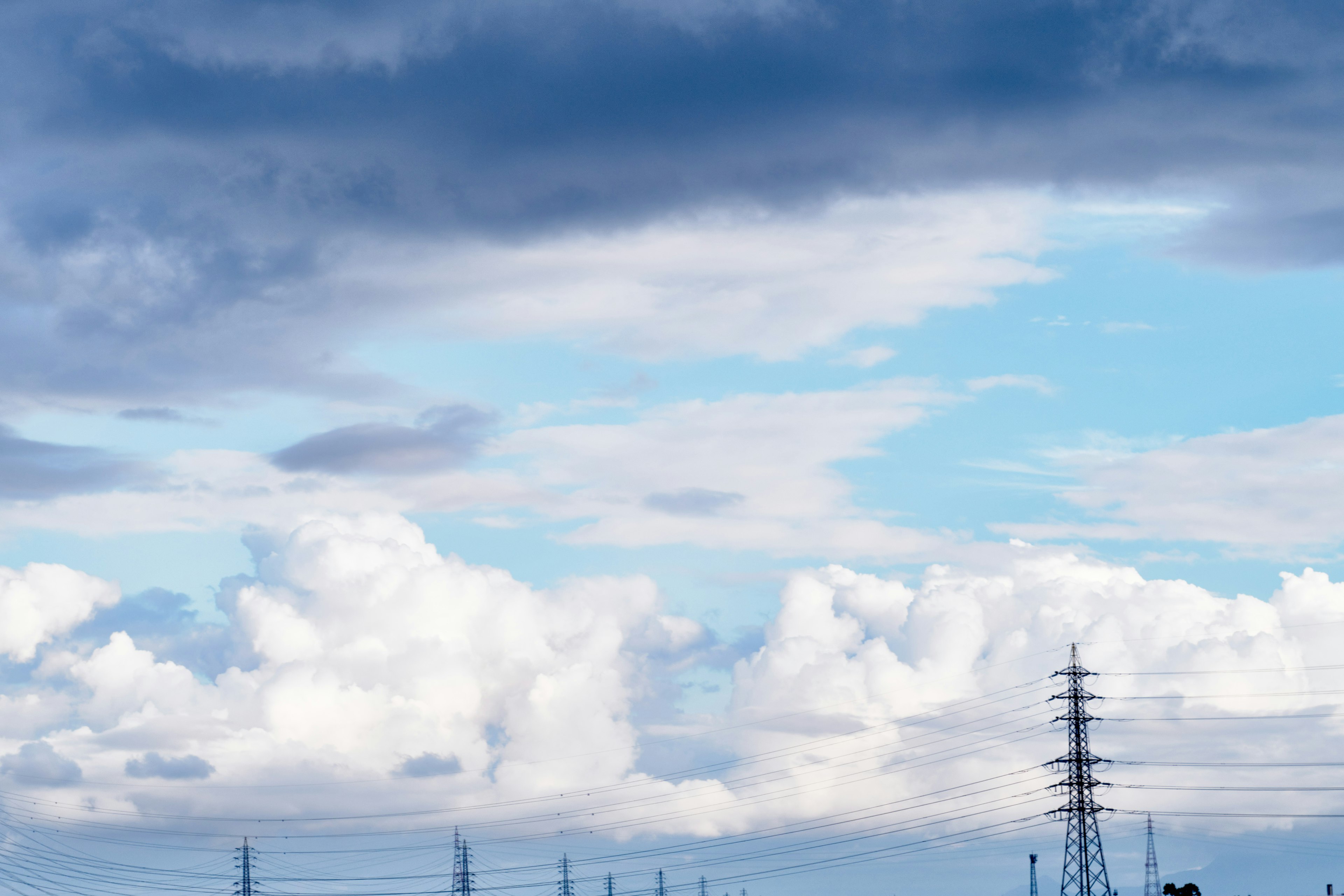 Landschaft mit blauem Himmel und weißen Wolken mit Stromleitungen