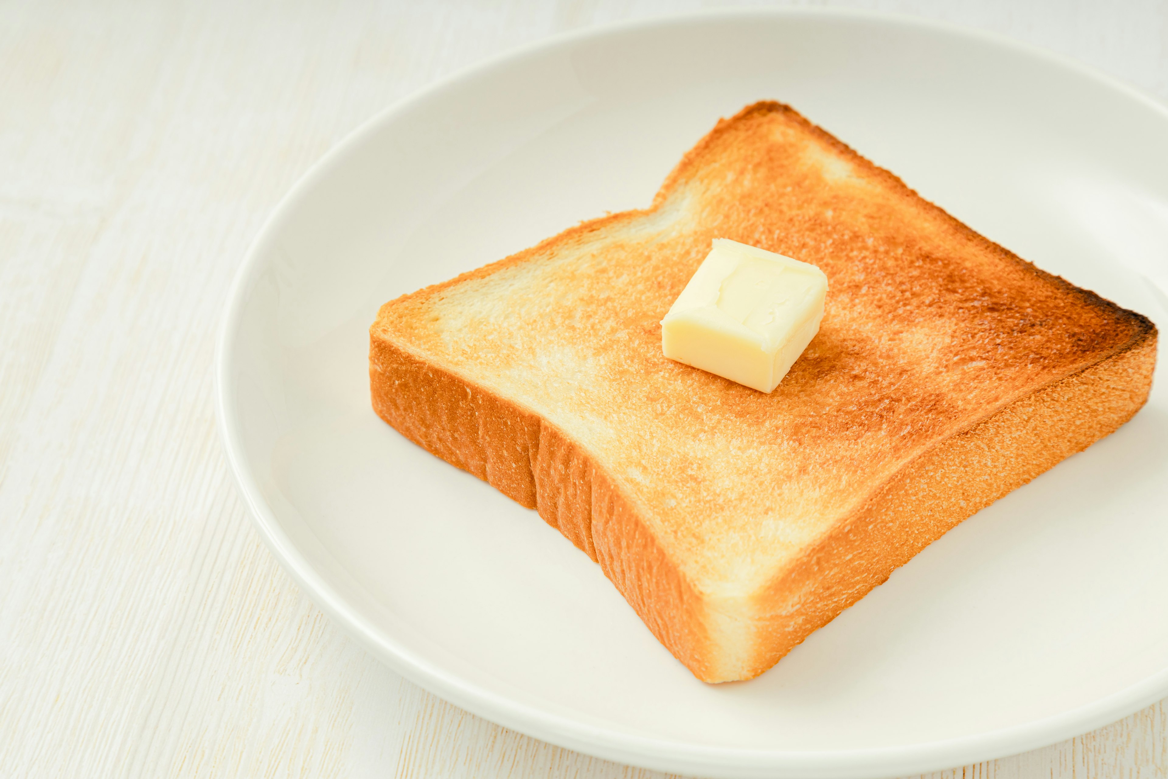 Toast mit einem Stück Butter auf einem weißen Teller