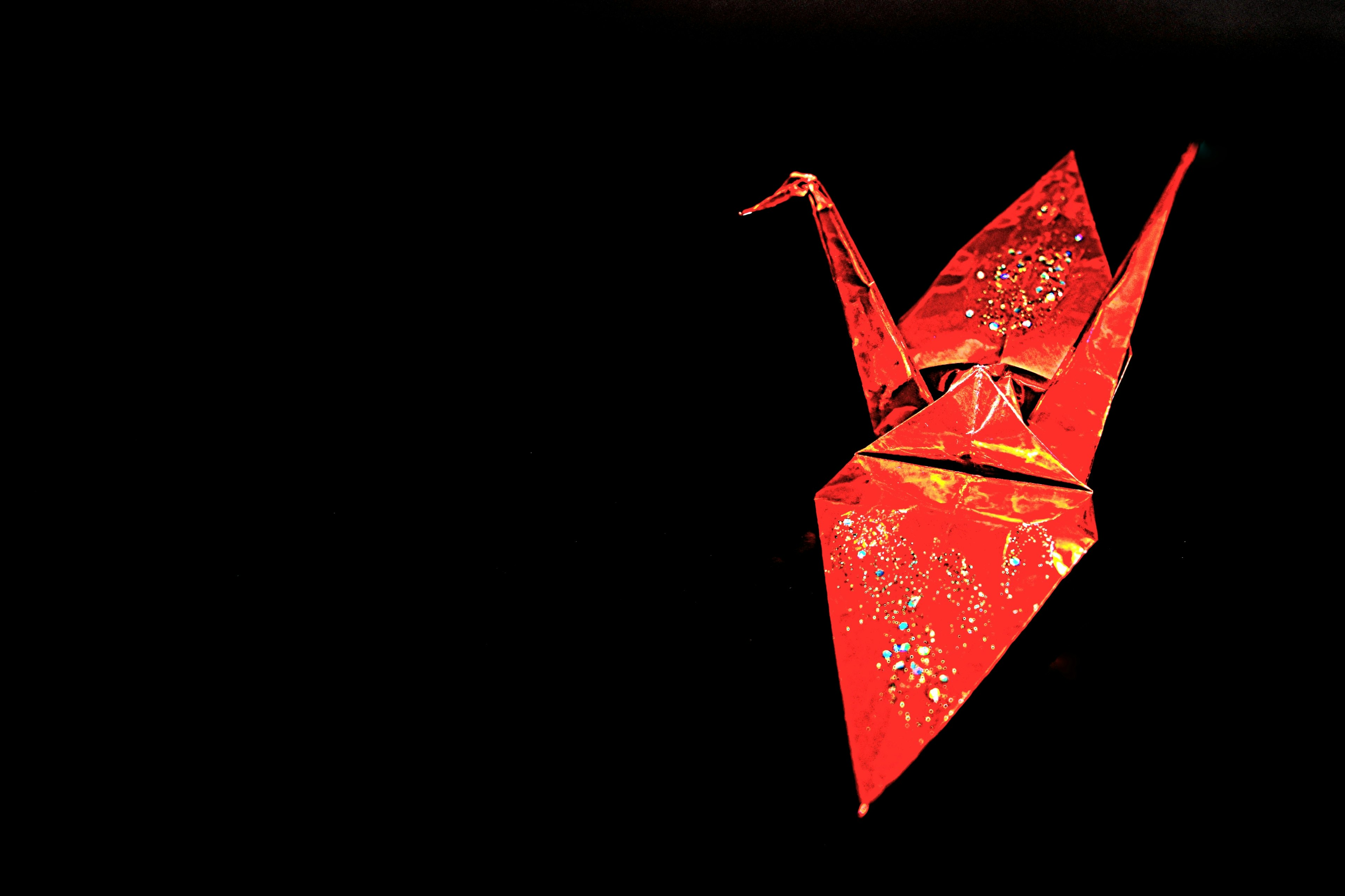 Red origami crane floating against a dark background