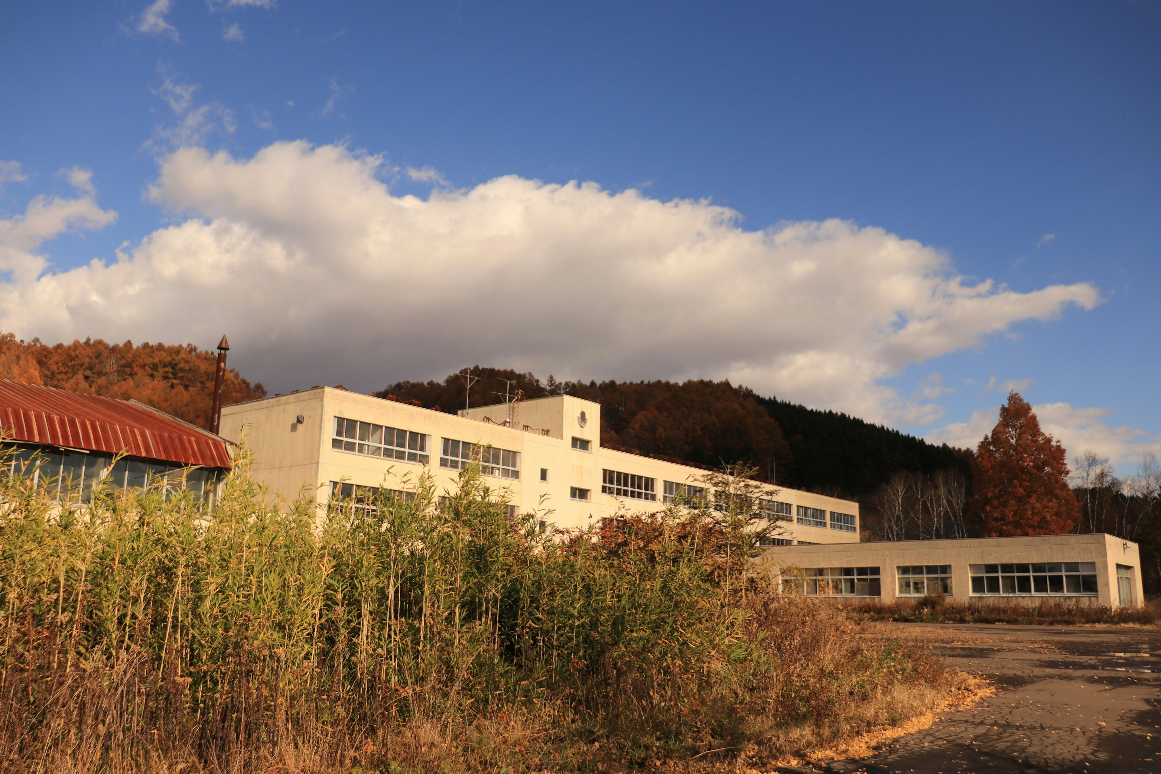 Altes Schulgebäude in der Nähe eines Berges mit blauem Himmel