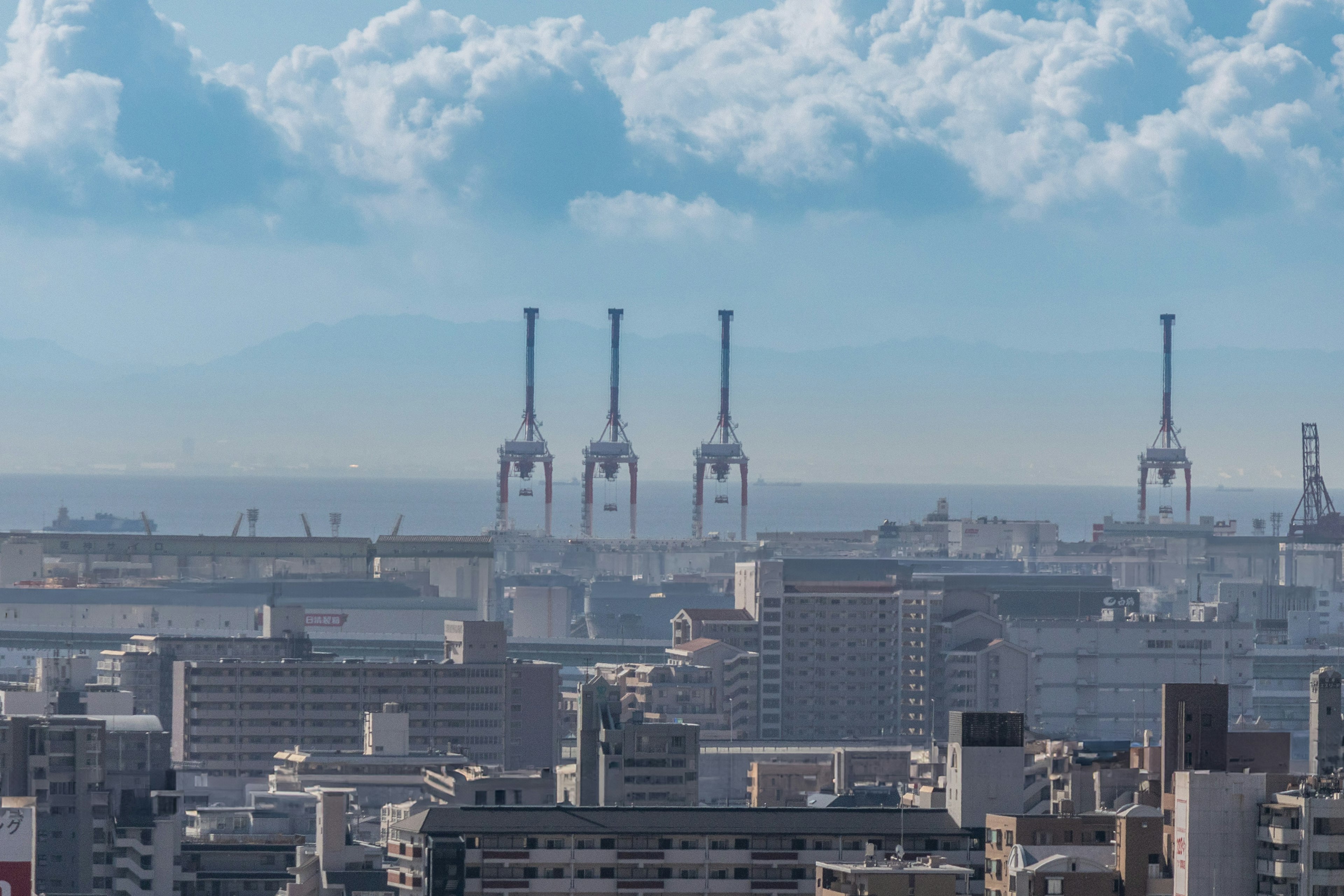 Paisaje urbano con chimeneas industriales y océano distante